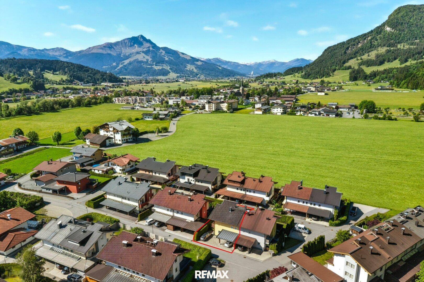 Luftaufnahme einer Wohnsiedlung in einer grünen Berglandschaft.