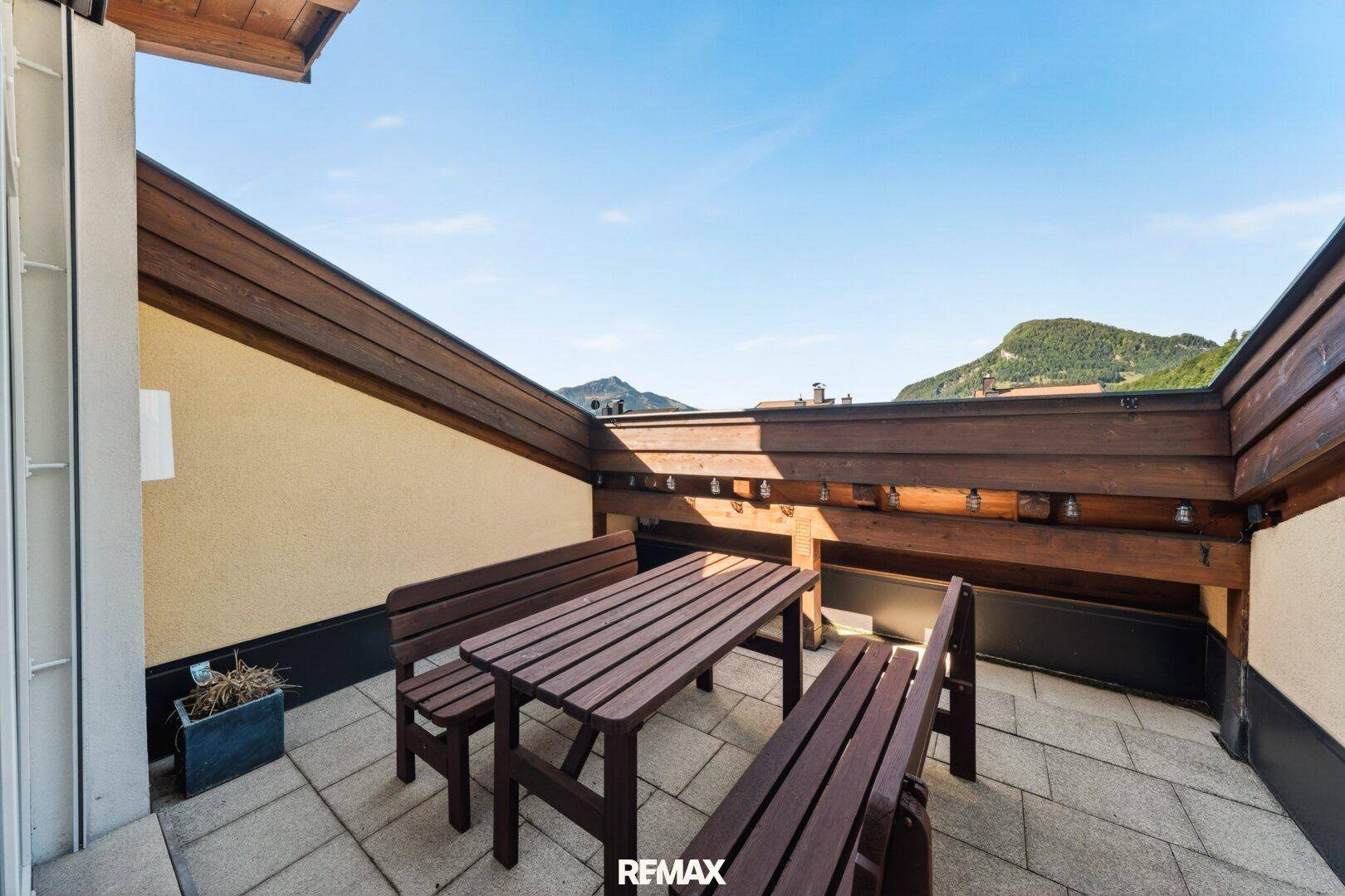 Große Dachterrasse mit Holztisch und Bergblick.