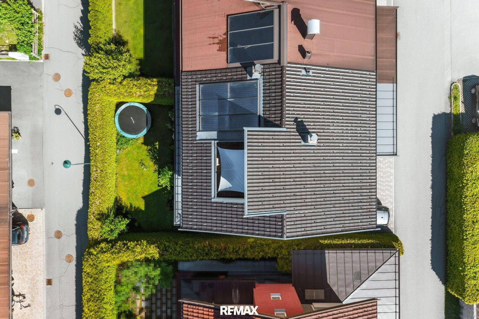 Luftaufnahme eines Hauses mit Garten, Trampolin und Dachfenstern.