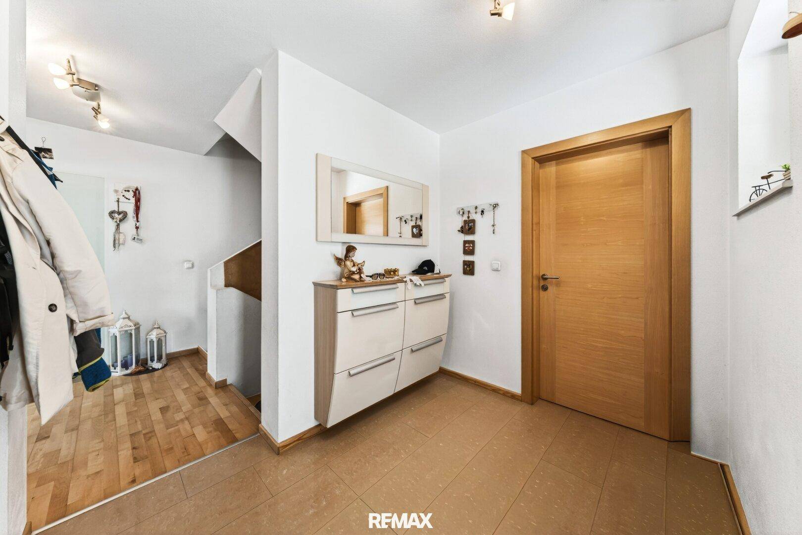 Eingangsbereich mit Garderobe, Spiegel und Holztüren.