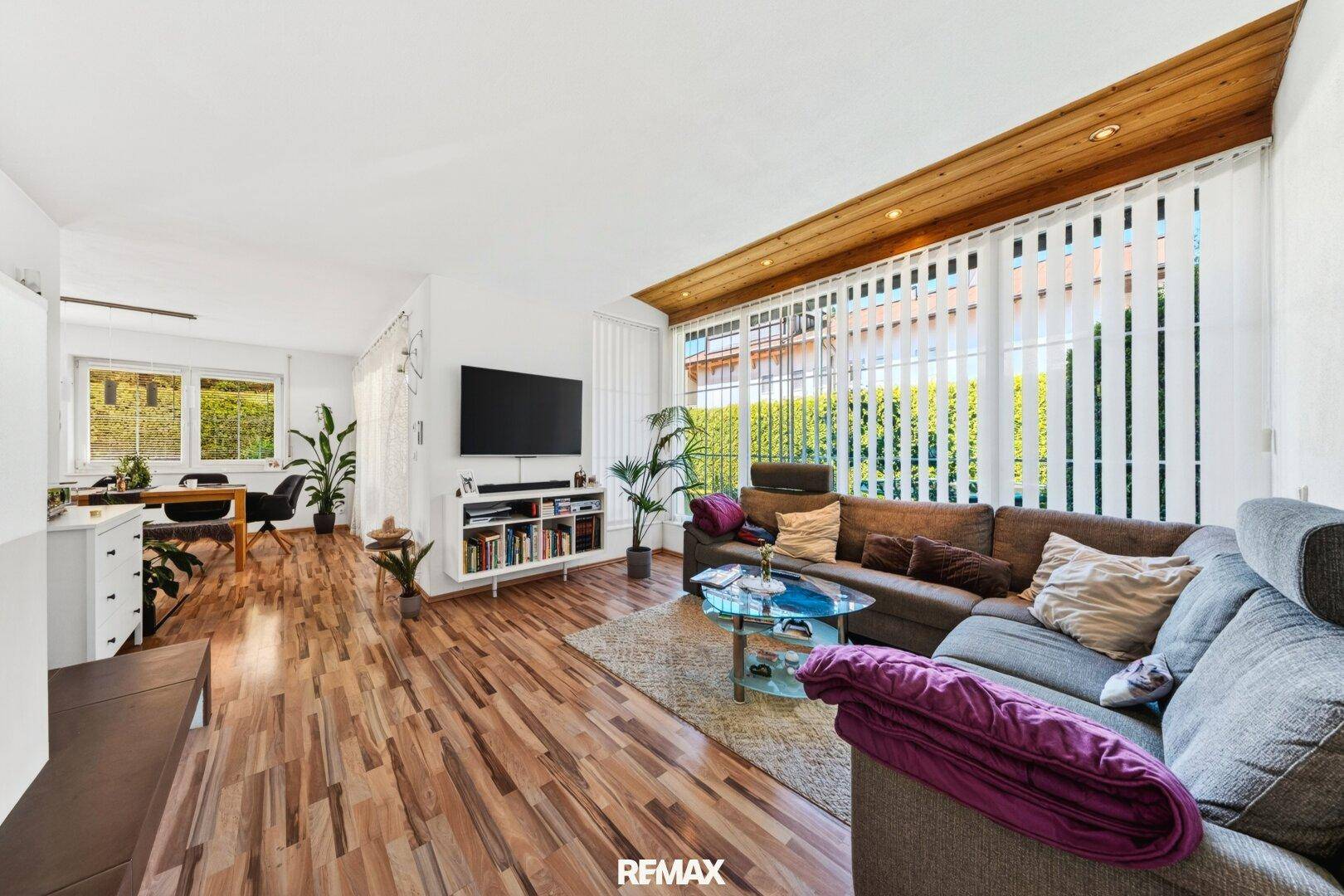 Gemütliches Wohnzimmer mit großem Sofa, Holzboden und vielen Fenstern für viel Tageslicht.