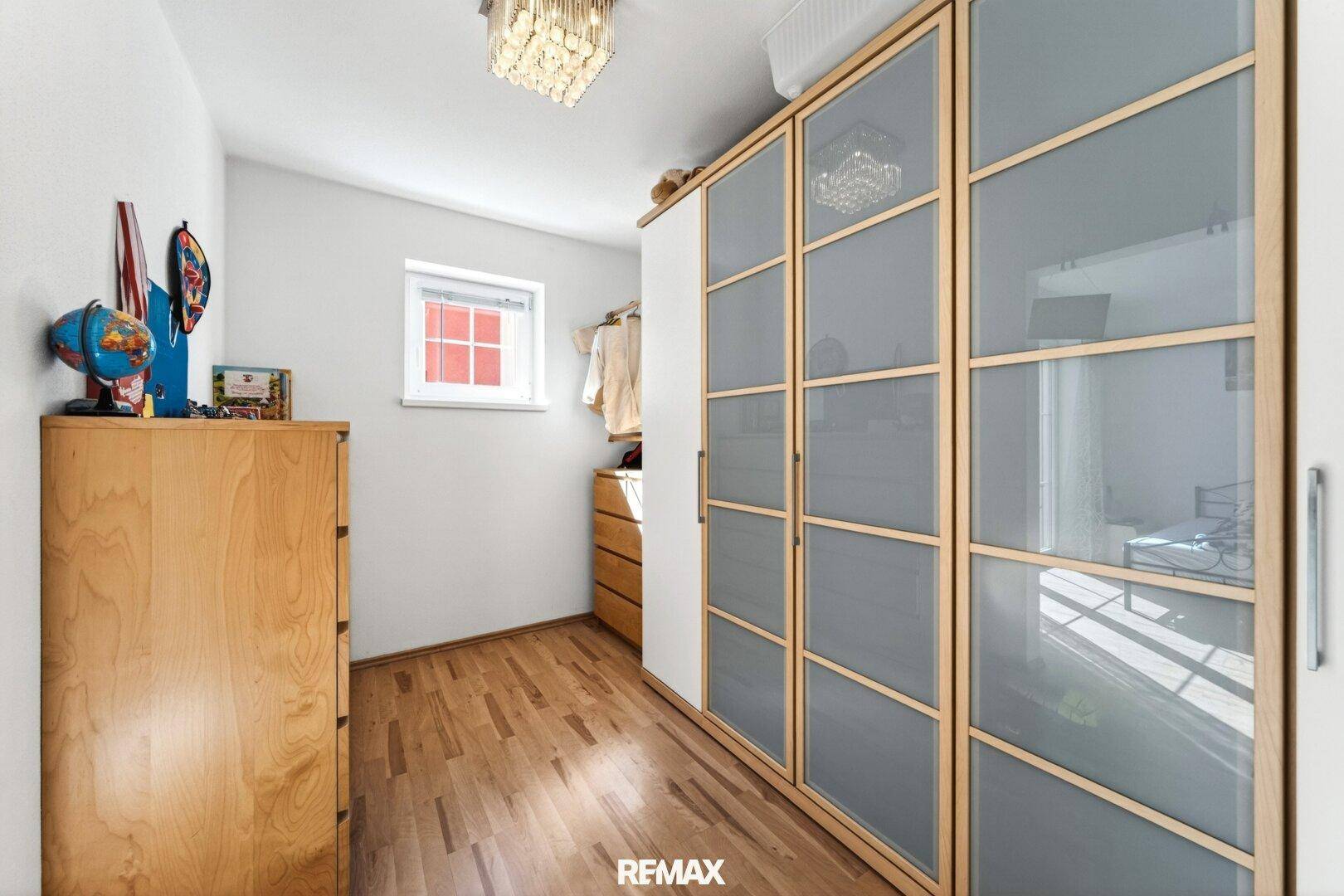 Ankleidezimmer mit Einbauschränken und Fenster.