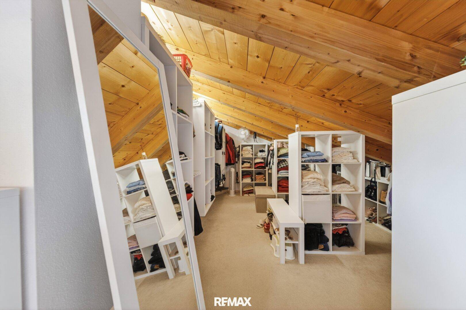 Ankleidezimmer im Dachgeschoss mit vielen Regalen und Spiegel.