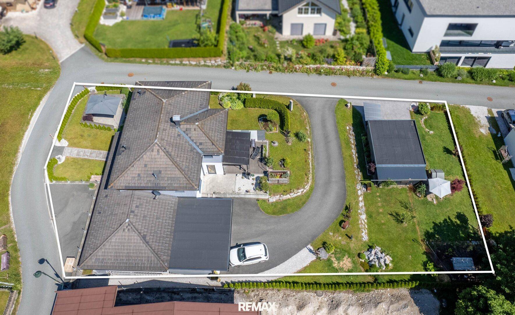 Luftaufnahme eines weitläufigen Anwesens mit großem Garten, Zufahrt und separatem Garagengebäude.
