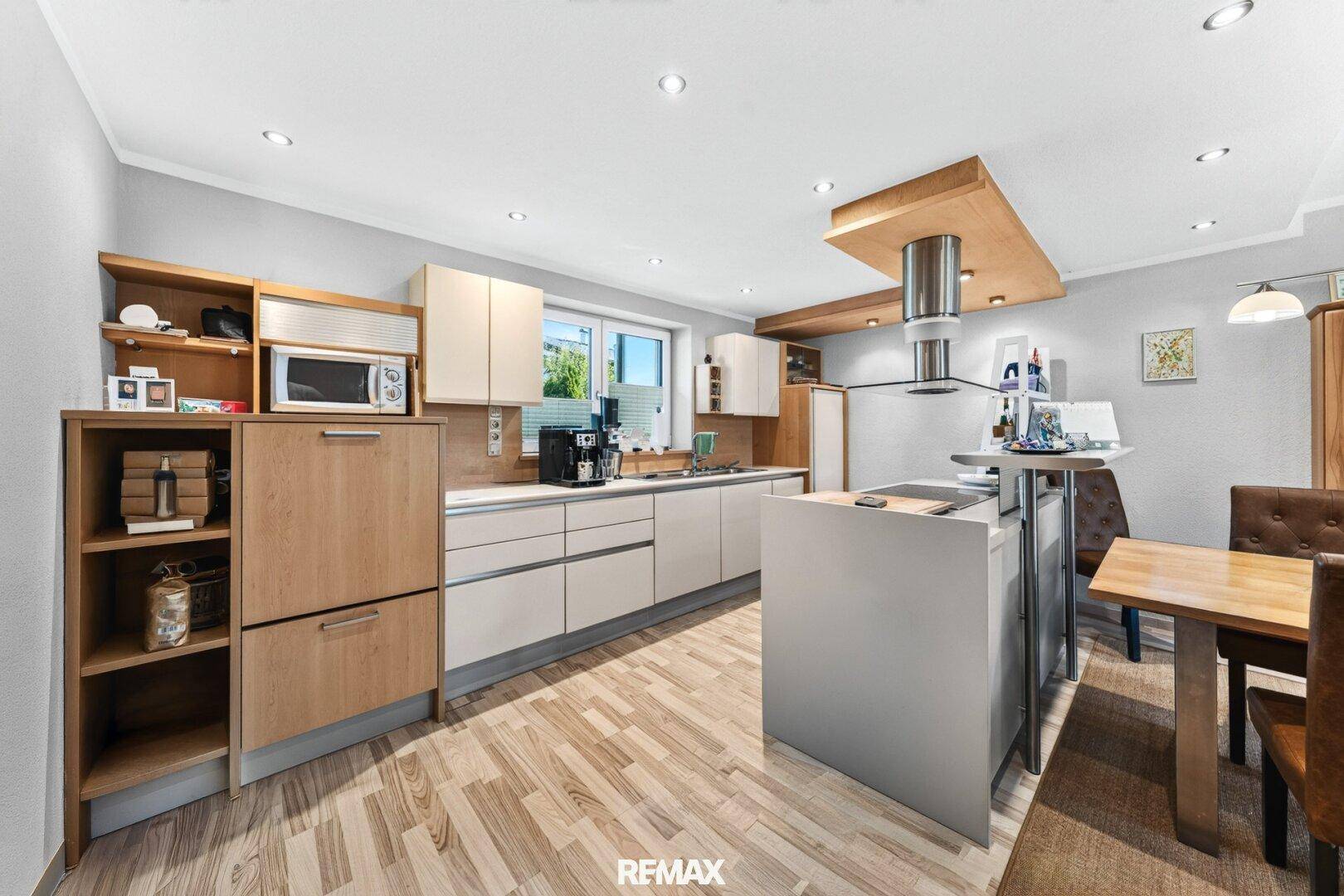 Moderne offene Küche mit heller Holzoptik, Kücheninsel und integrierten Geräten.