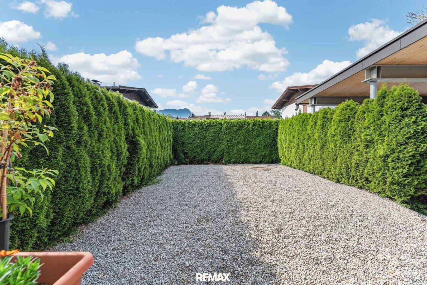 Kiesfläche umgeben von hohen Hecken, ideal als Parkplatz oder privater Hofbereich.