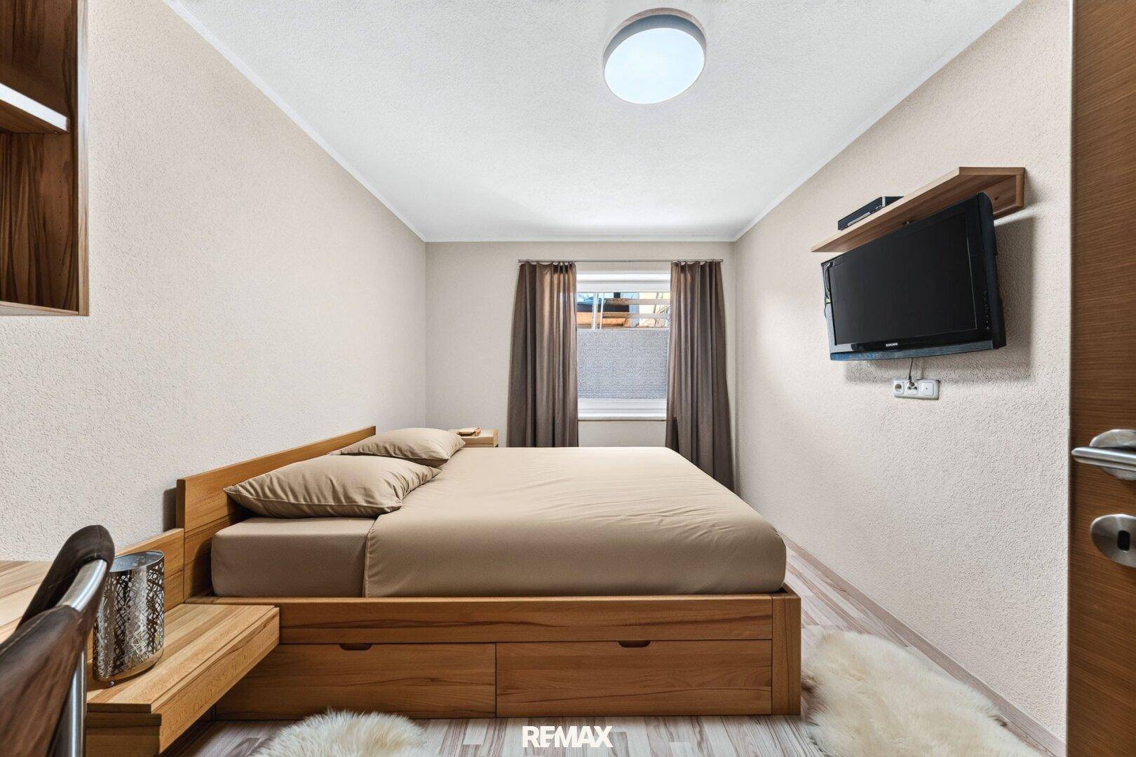 Gemütliches Schlafzimmer mit Holzbett, Stauraum und einem kleinen Fenster.