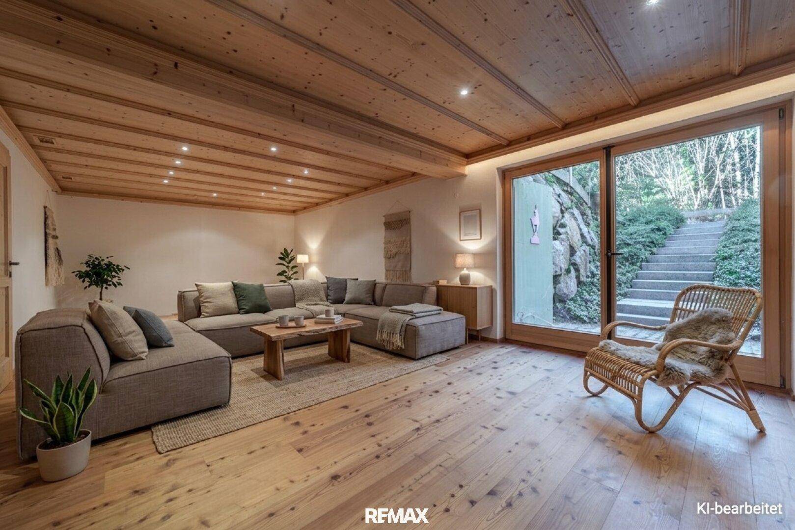 Gemütliches Wohnzimmer mit großem Sofa, Holzboden und Zugang zu einer Außentreppe.