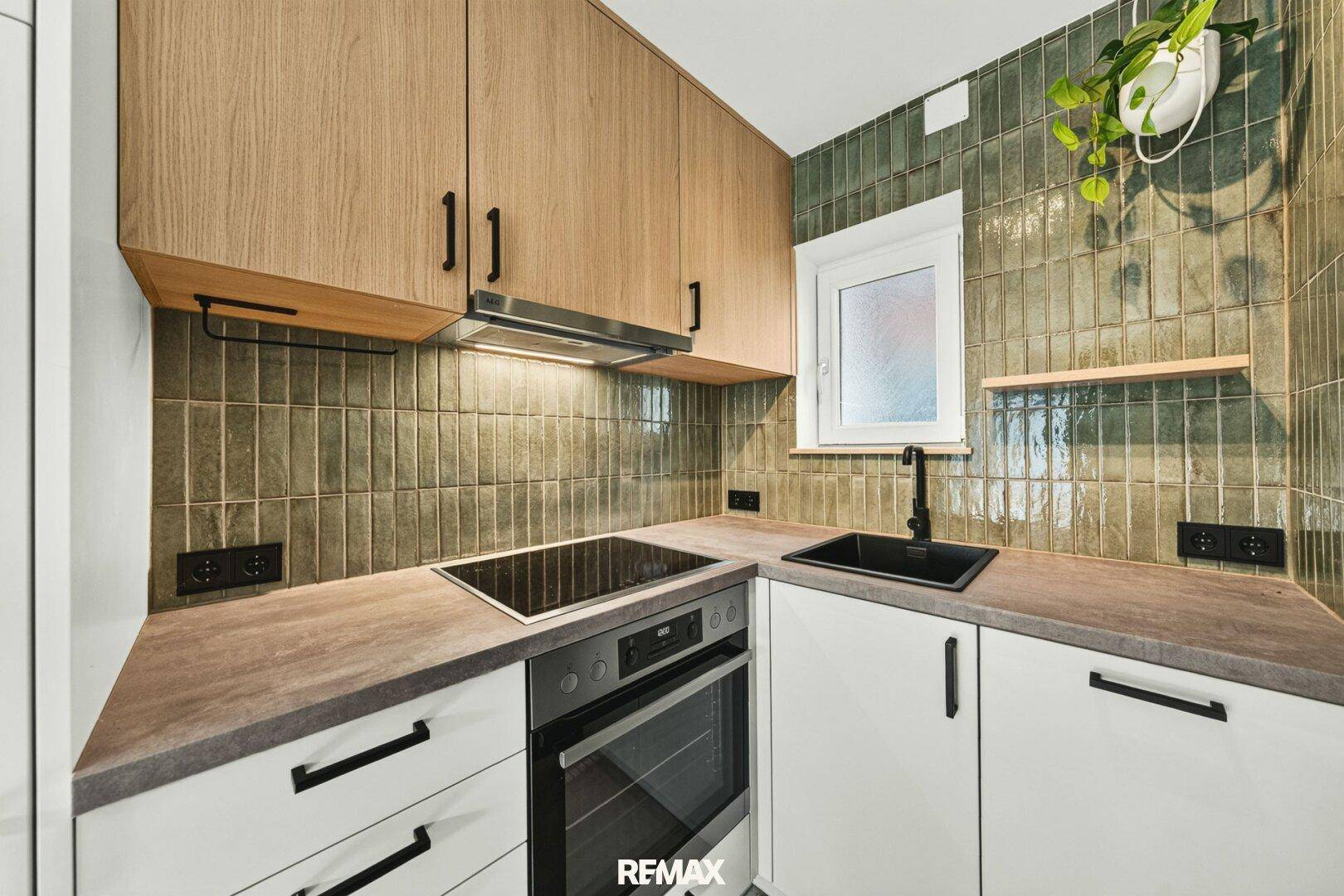 Moderne Küche mit Holzschränken, grünen Fliesen und Induktionskochfeld.