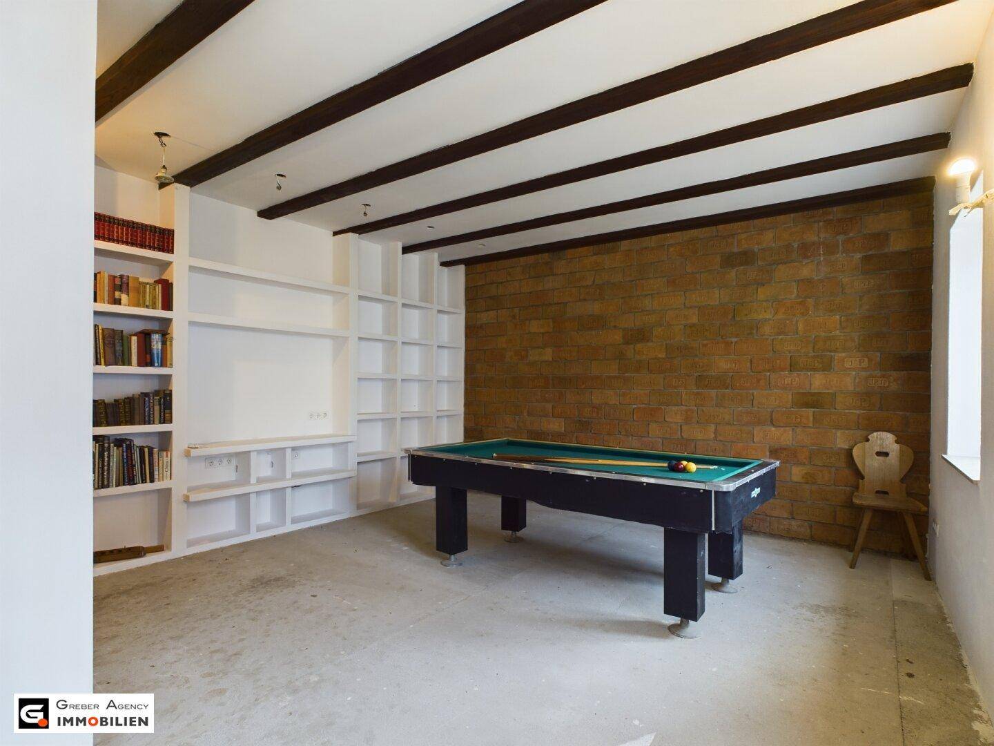 Spielzimmer mit Billardtisch, eingebauten Regalen und einer Akzentwand aus Ziegeln.