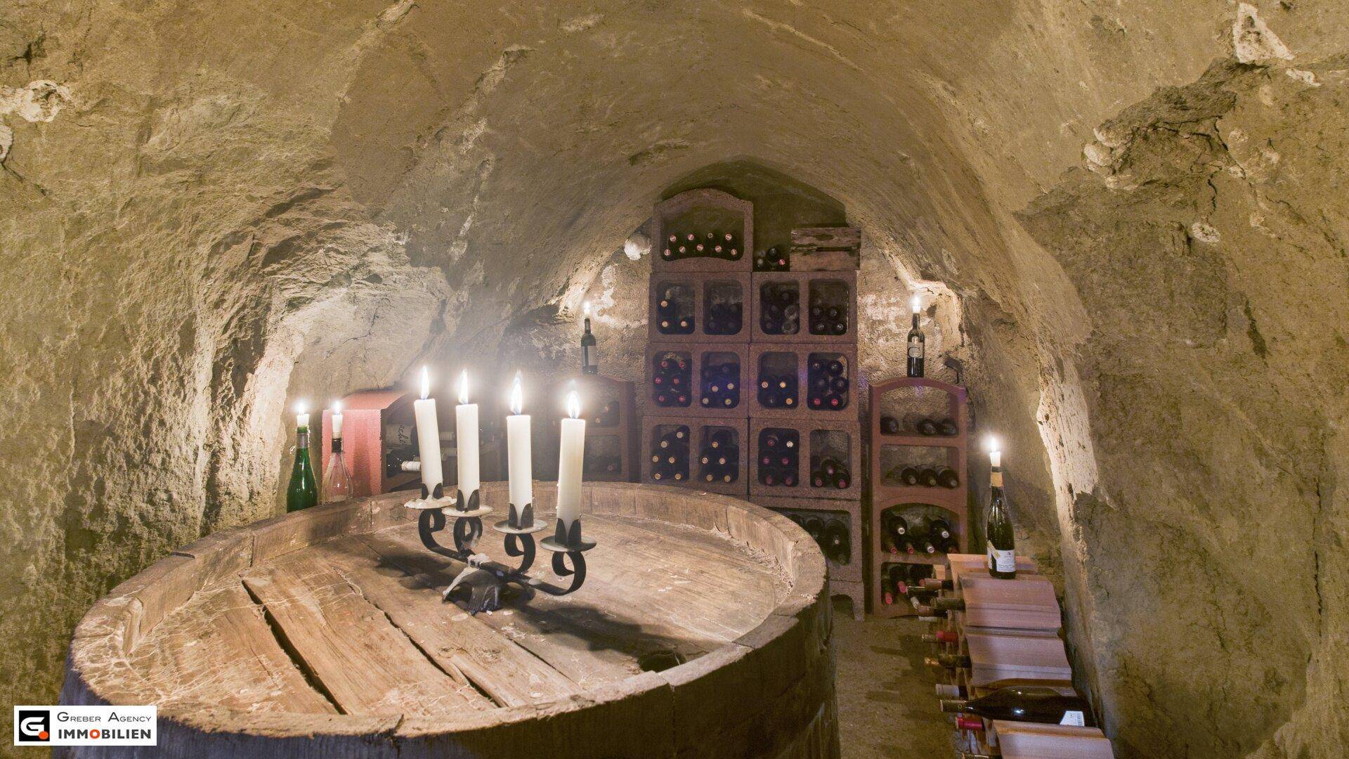 Gemütlicher Weinkeller mit Weinflaschen in Regalen, einem großen Holzfass und warmem Kerzenlicht, das die Umgebung erhellt.