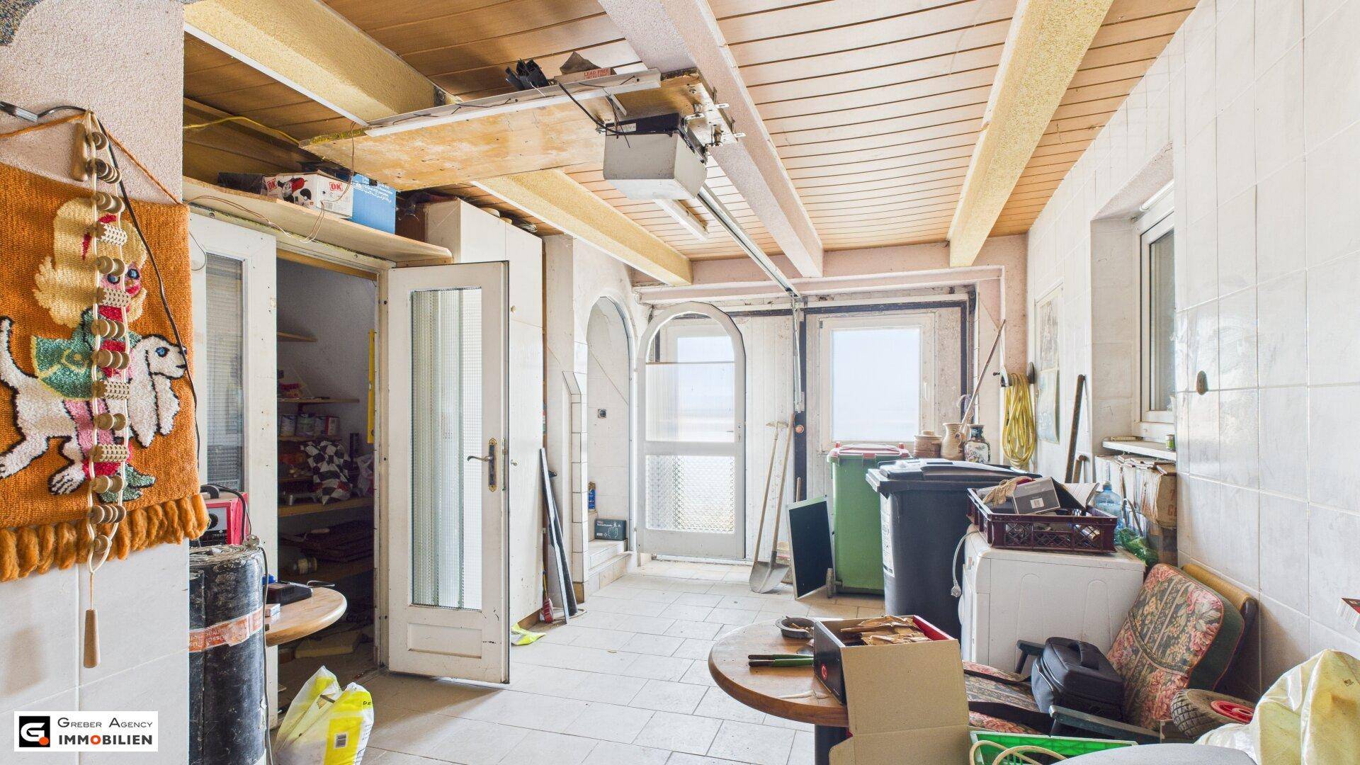 Geräumiger Abstellraum mit Fliesenboden, Holzdecke und verschiedenen Lagergegenständen.