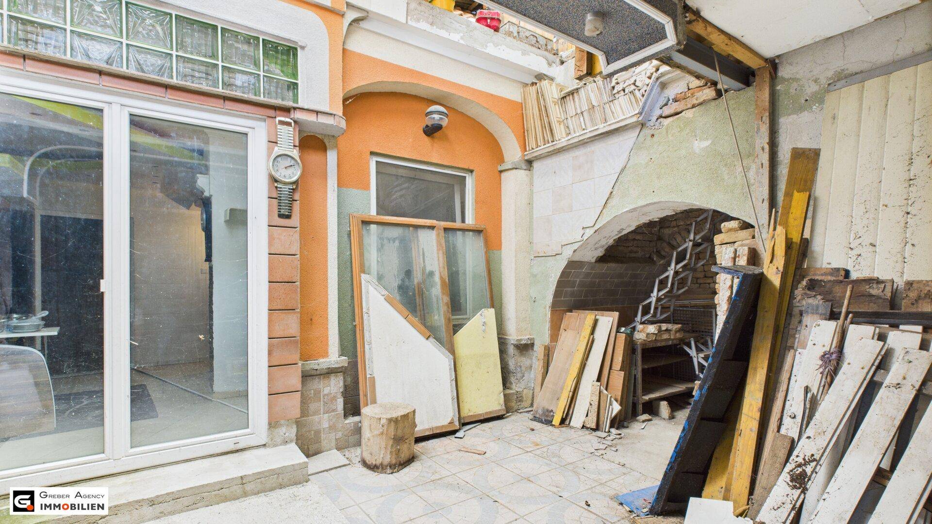 Baustelle im Innenbereich mit Fenstern, Böden und verschiedenen Baumaterialien, die auf Renovierung hindeuten.