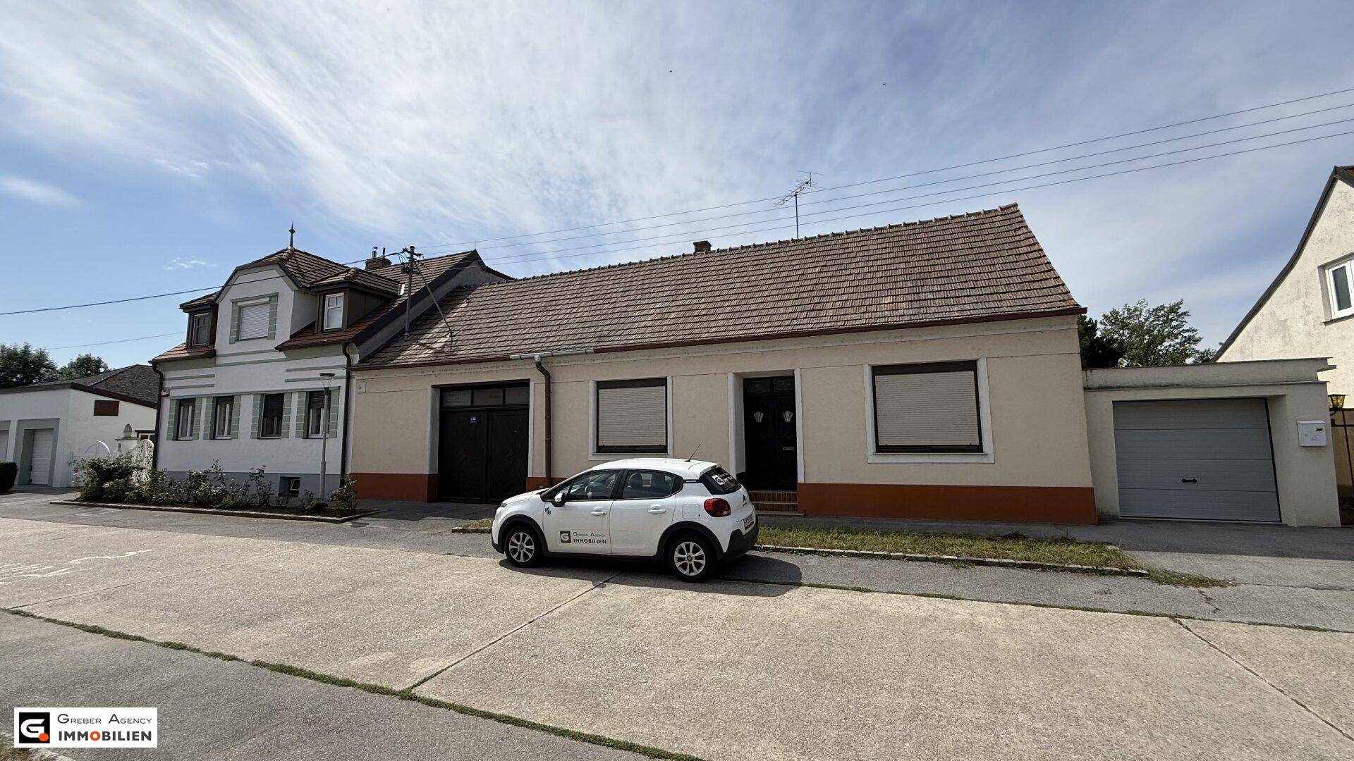 Weitwinkelaufnahme eines Einfamilienhauses mit angrenzender Garage und Satteldach an einer Straße.