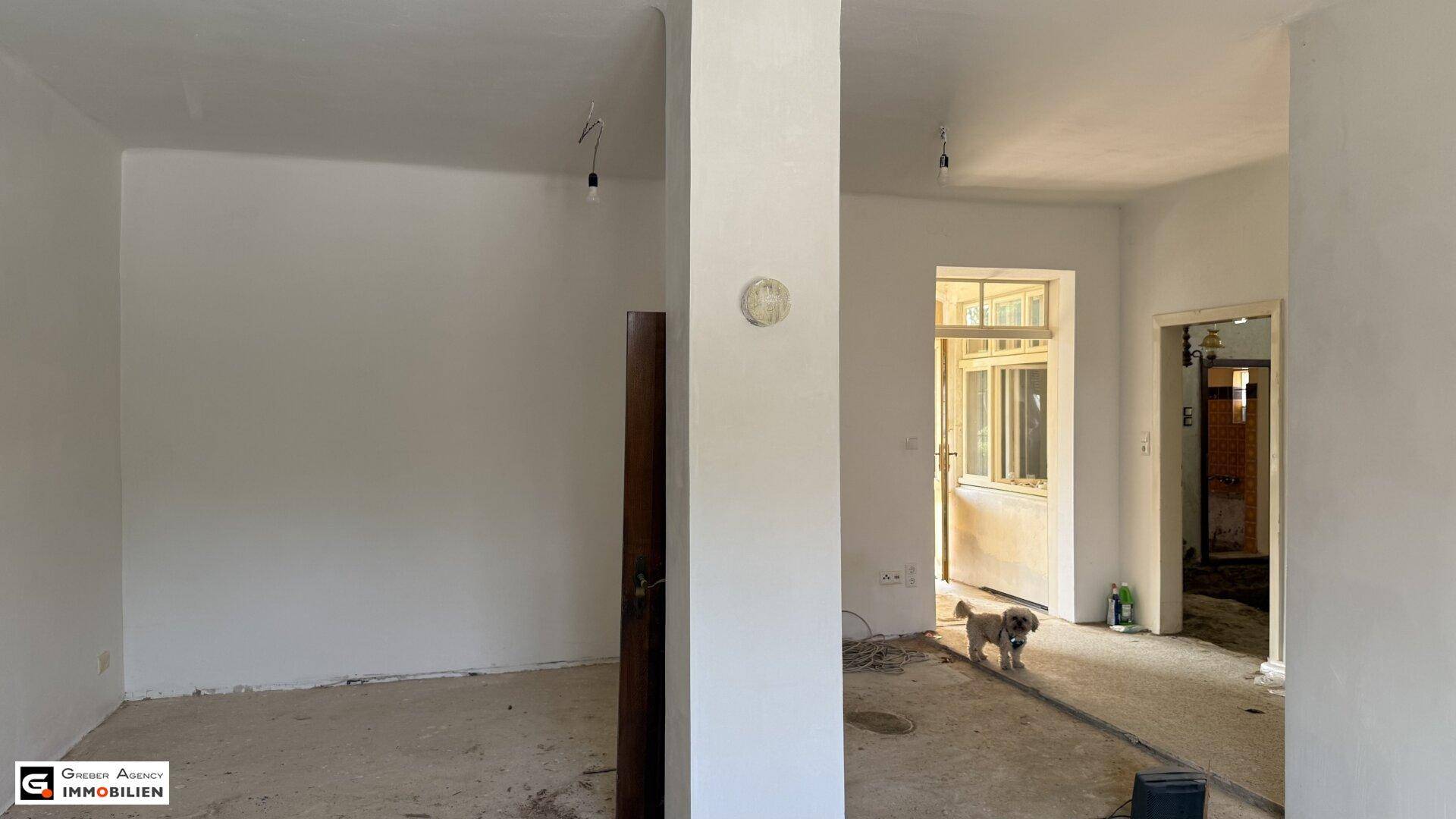 Innenraum im Rohzustand mit freigelegten Wänden und Blick auf den Eingangsbereich.