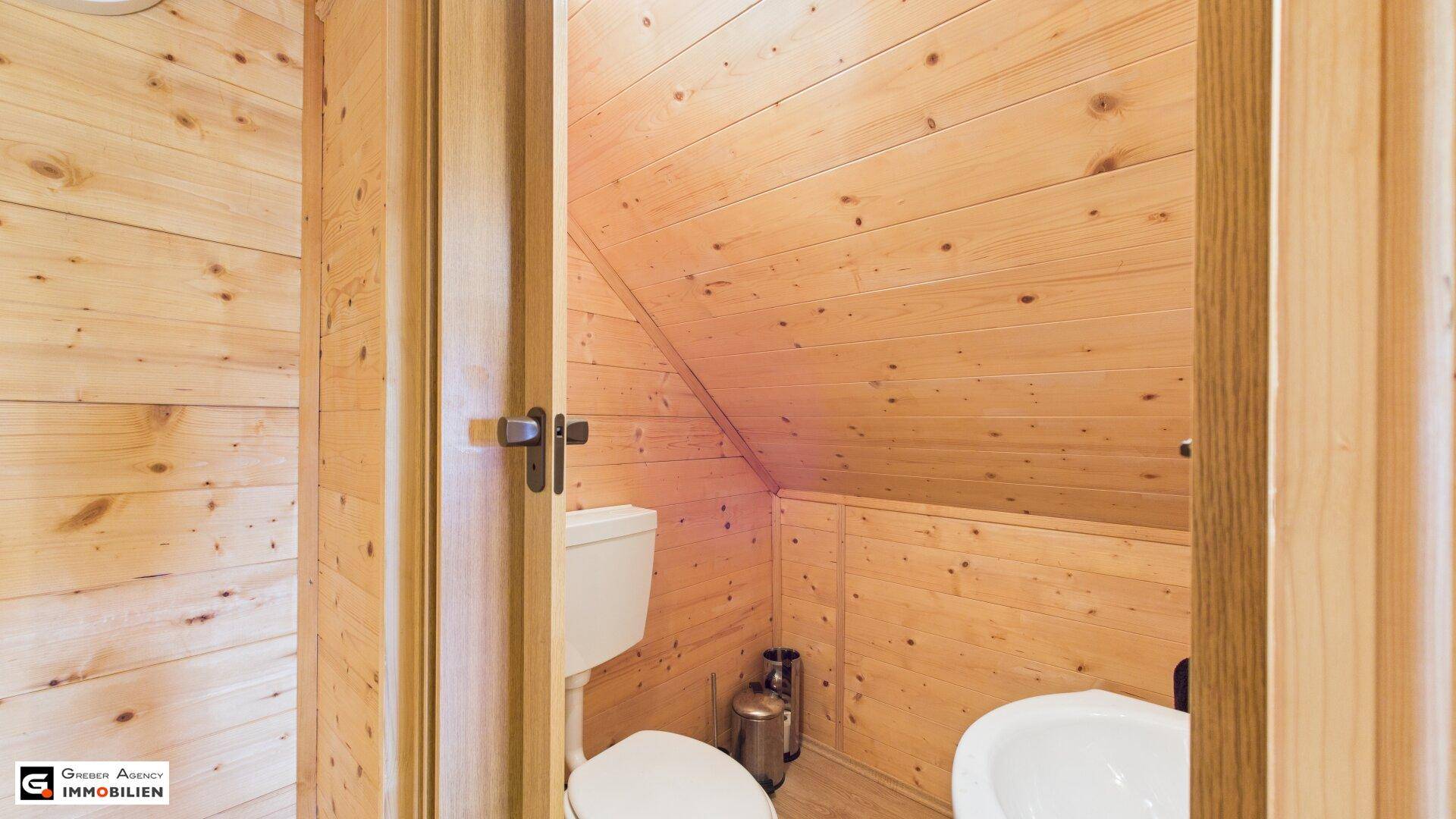 Kleiner WC-Raum im Dachgeschoss mit Holzverkleidung, Dachschräge und einfacher Ausstattung.