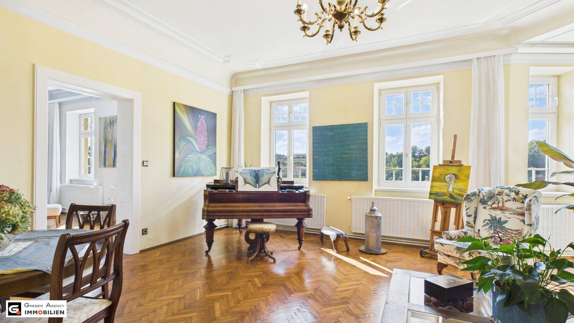 Elegantes Wohnzimmer mit Klavier, Parkettboden und Kronleuchter, durchflutet von Tageslicht.