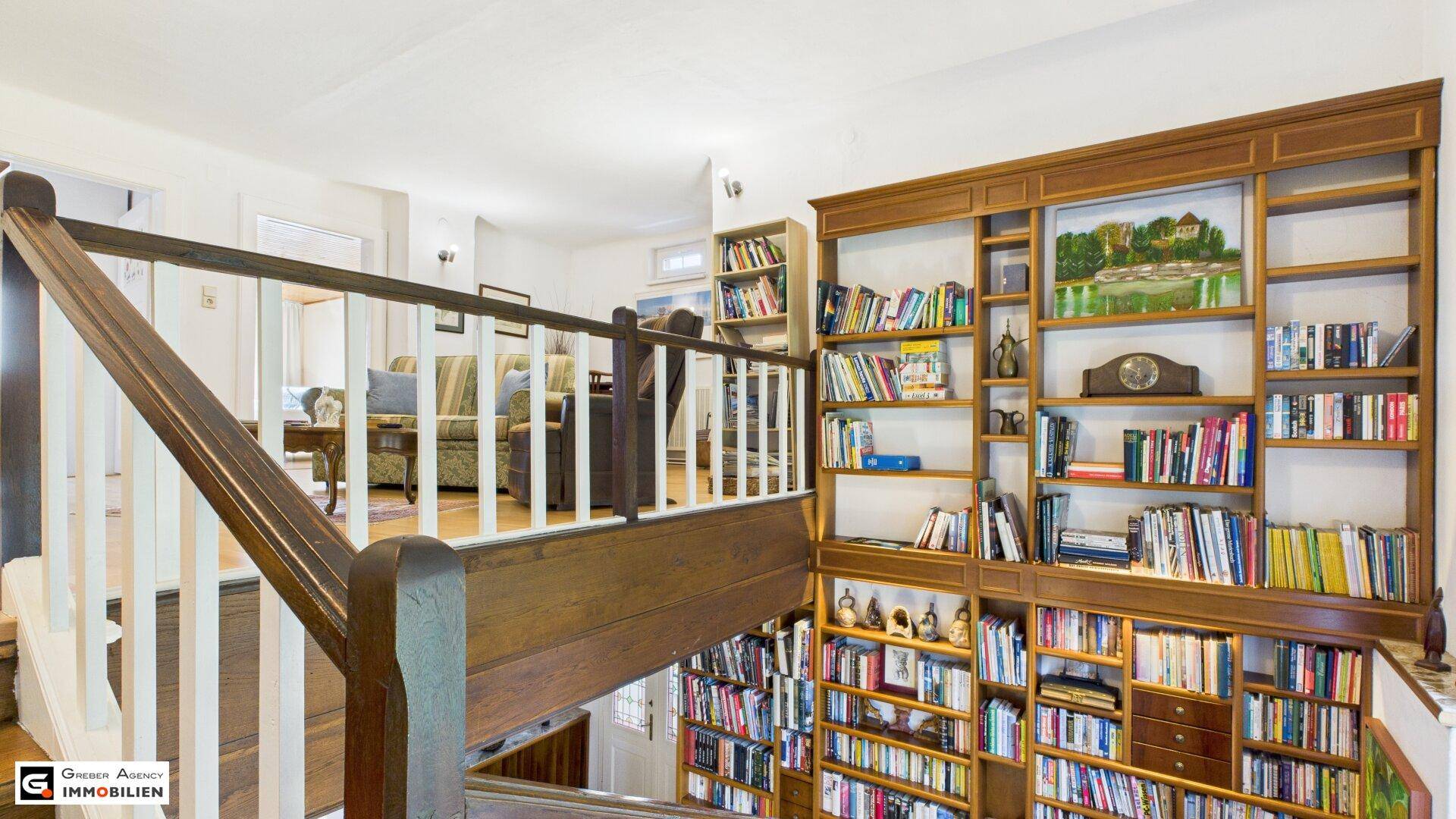 Treppenaufgang mit Holzgeländer und großem, eingebautem Bücherregal.