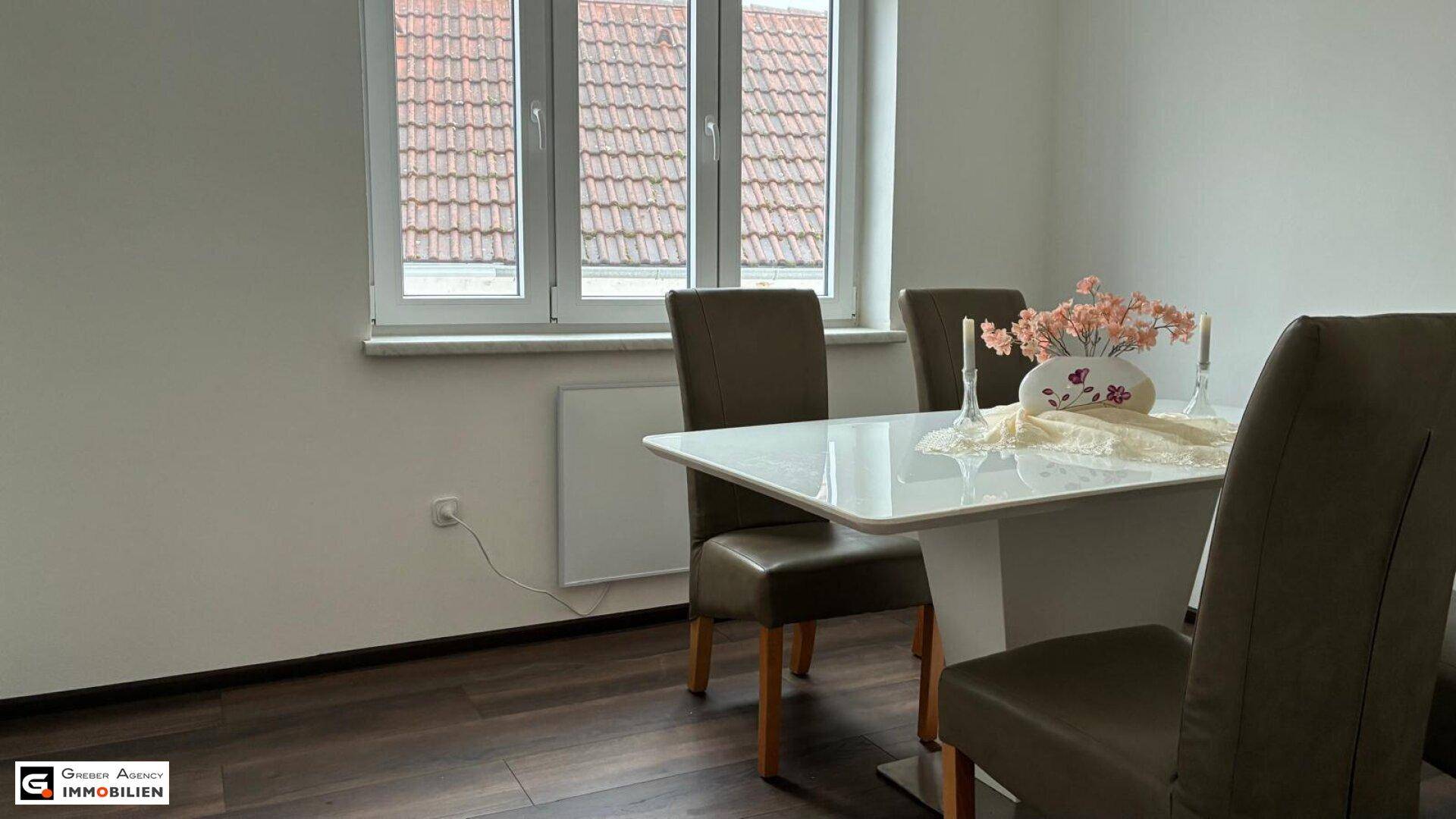 Essbereich mit Blick auf das Fenster, das Tageslicht hereinlässt, und einem modernen Esstisch.