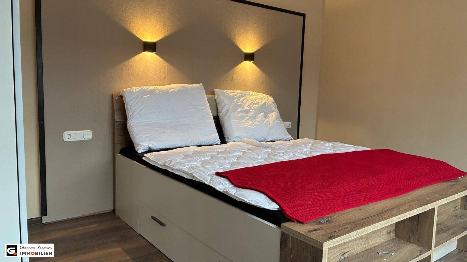 Gemütliches Schlafzimmer mit Doppelbett, Nachttischlampen und Stauraum unter dem Bett.