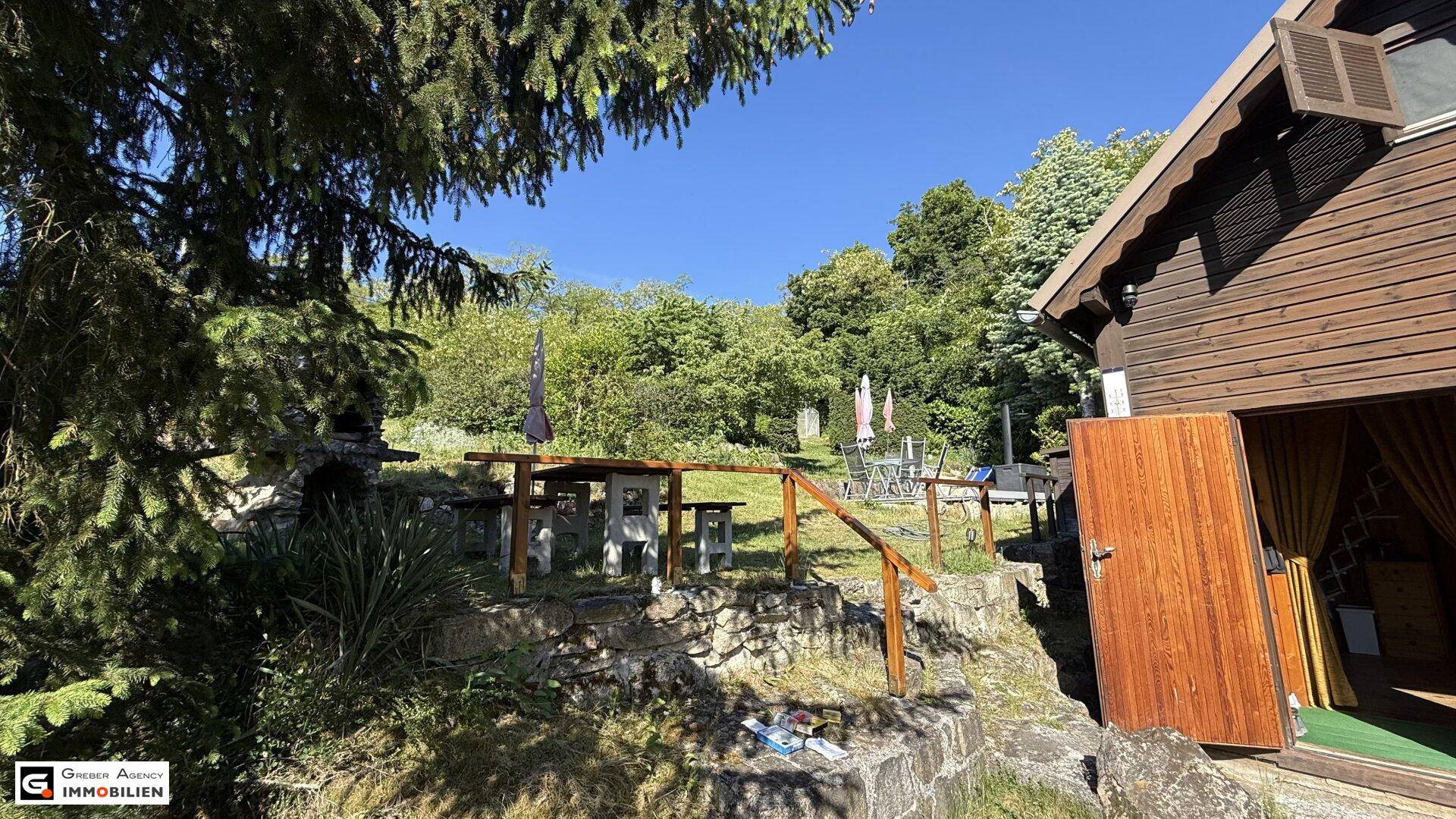 Eingangsbereich des Holzhauses mit angrenzendem Essbereich im Freien und Steinterrassen.