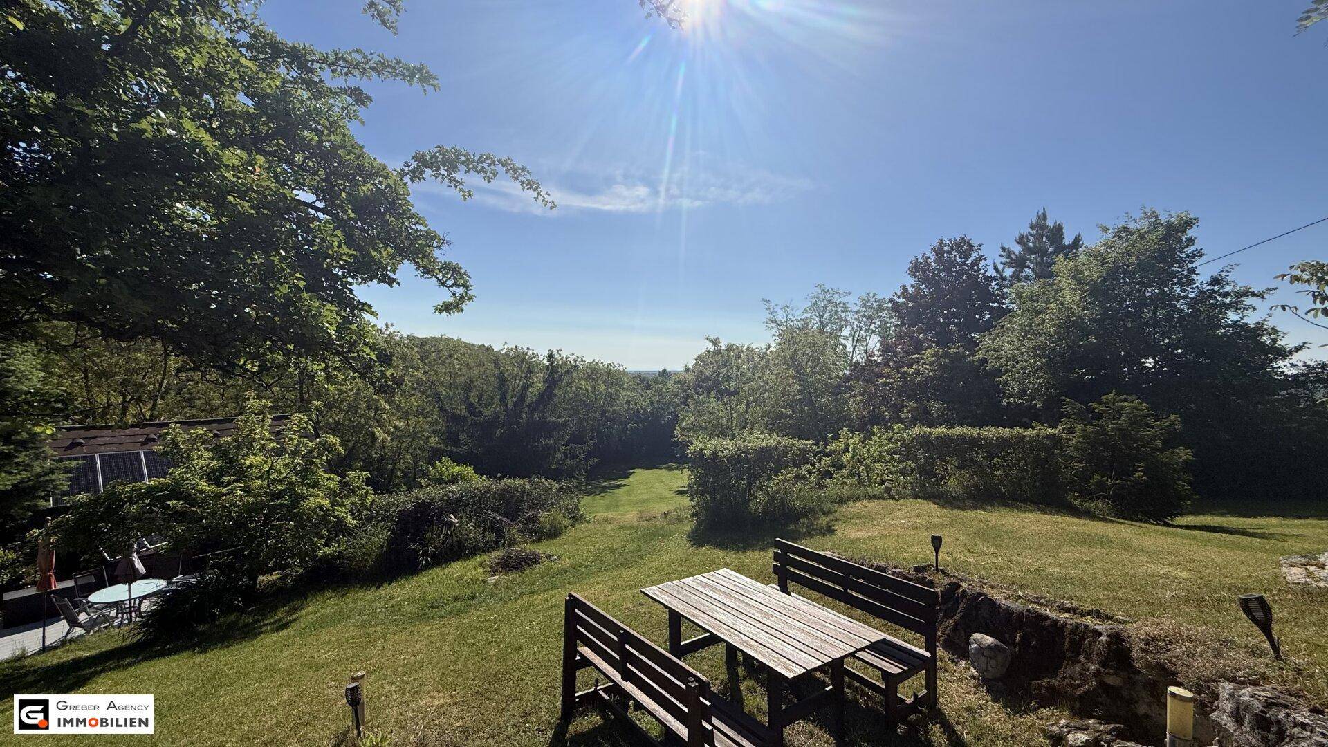 Gemütlicher Sitzbereich im Garten mit weitem Blick über die grüne Landschaft.