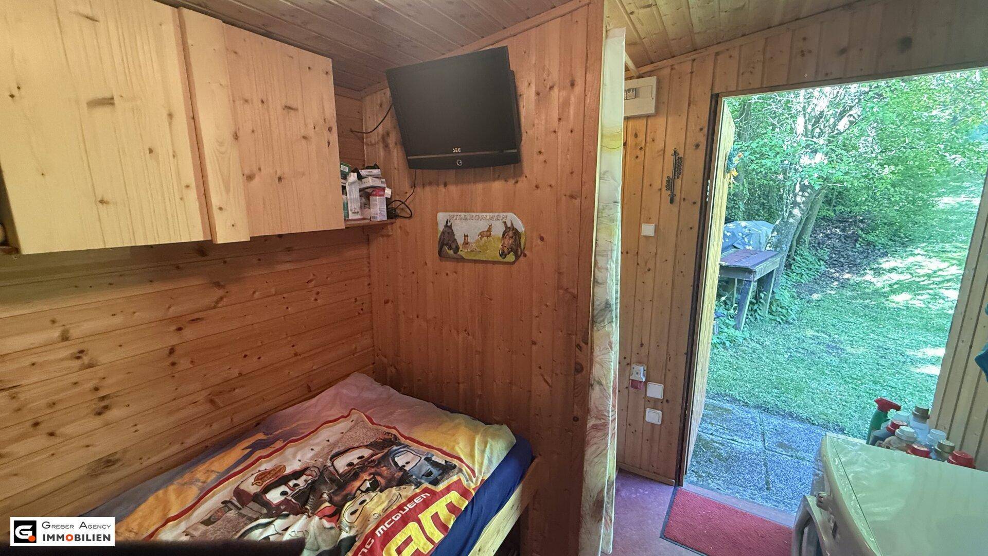 Schlafzimmer mit Holzwänden und direktem Zugang nach draußen, einfach und funktional.