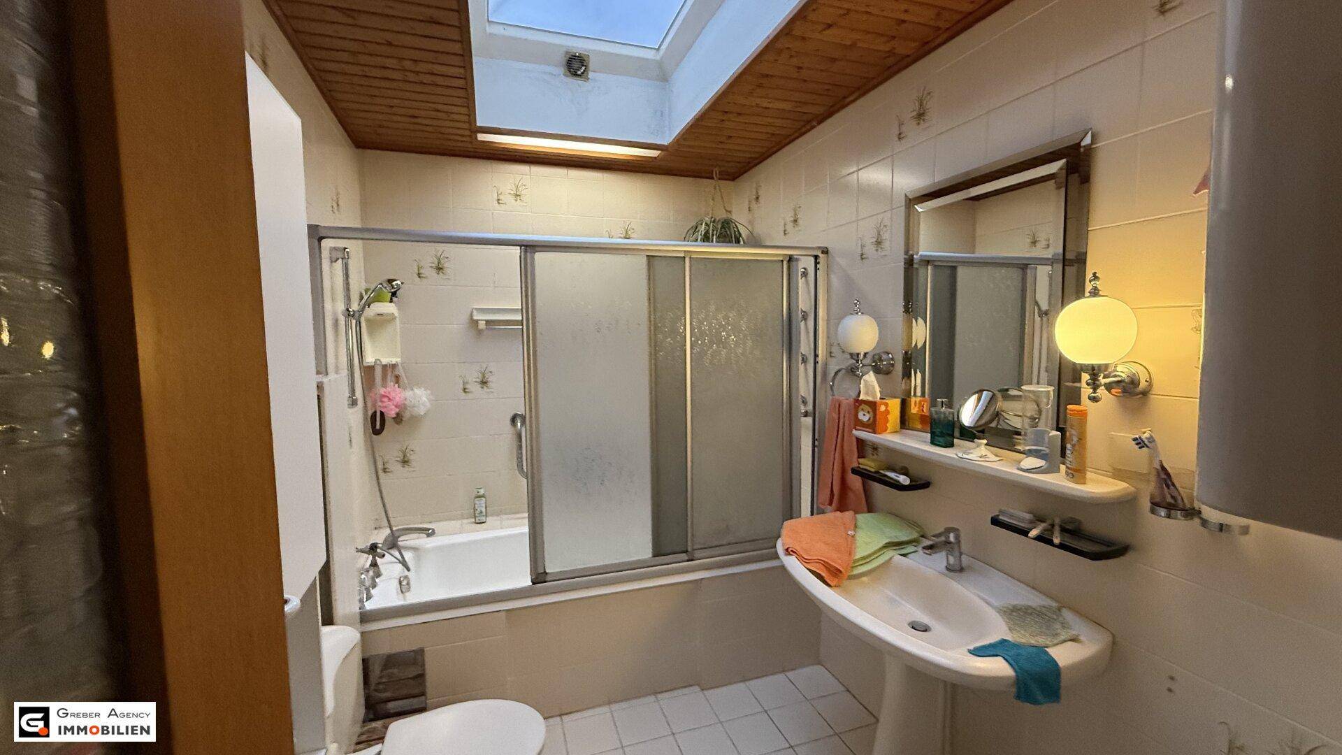 Badezimmer mit Badewanne, Duschkabine, Waschbecken und Oberlicht für Helligkeit und Belüftung.
