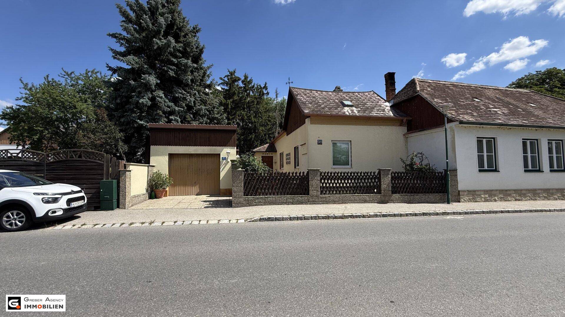 Ansicht des Hauses von der Straße mit Garage und gepflegtem Vorgarten unter blauem Himmel.