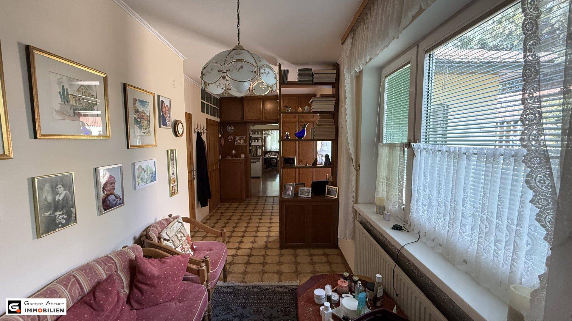 Heller Flur mit Fenster, Heizkörper und Holzregalen, der zu weiteren Räumen führt.