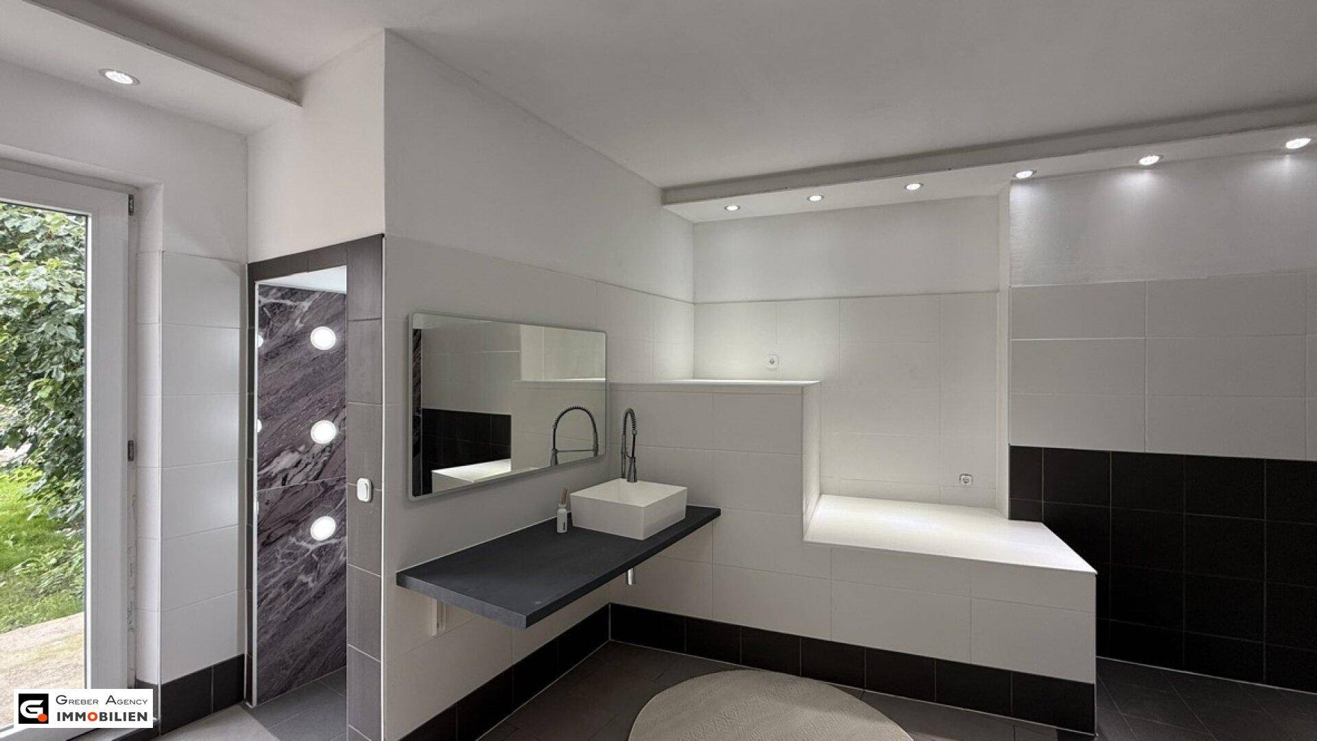 Helles Badezimmer mit modernem Waschbecken, Spiegel und Zugang zum Garten.