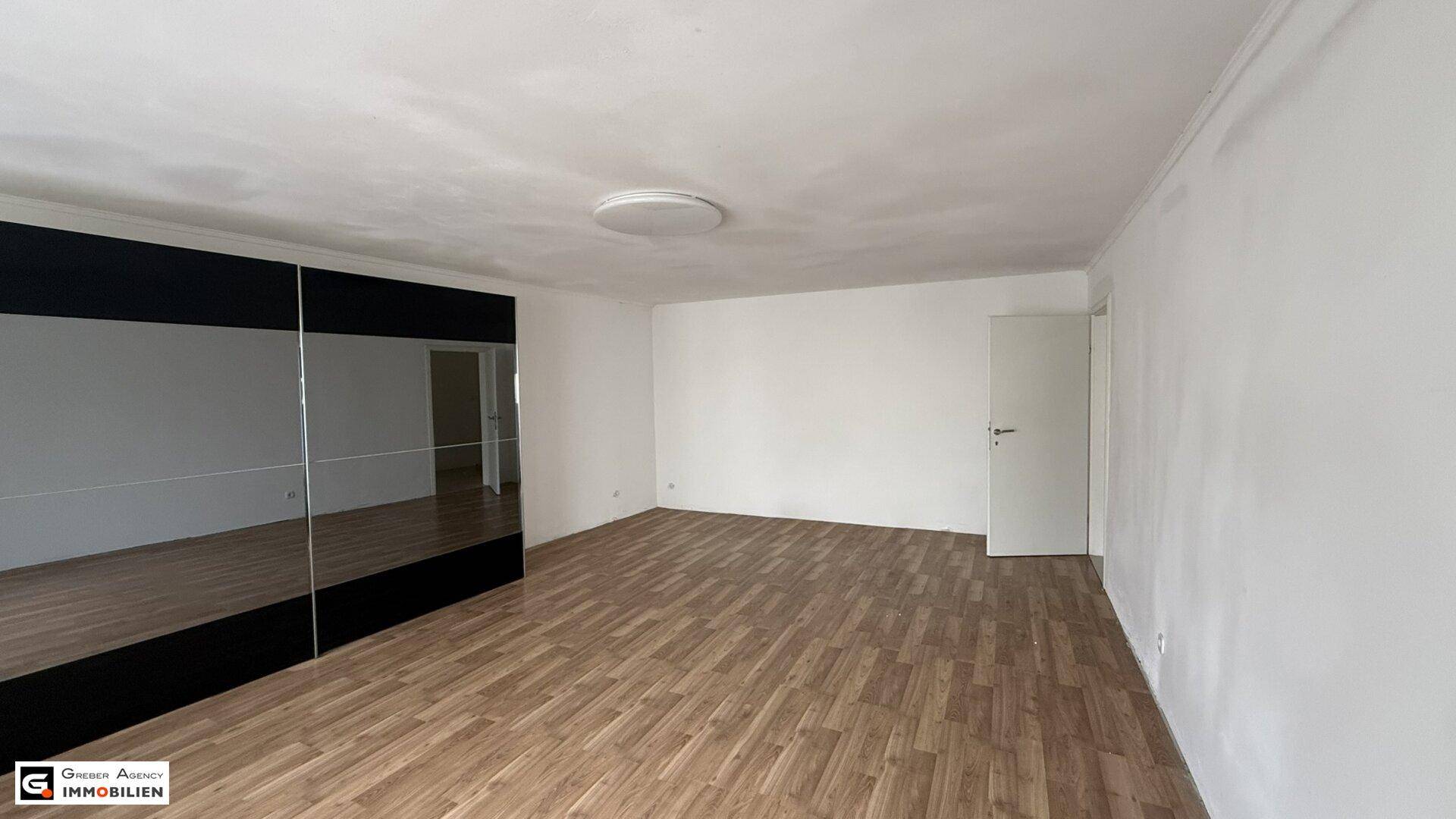 Helles Schlafzimmer mit Holzboden, großem Spiegelschrank und viel Platz.