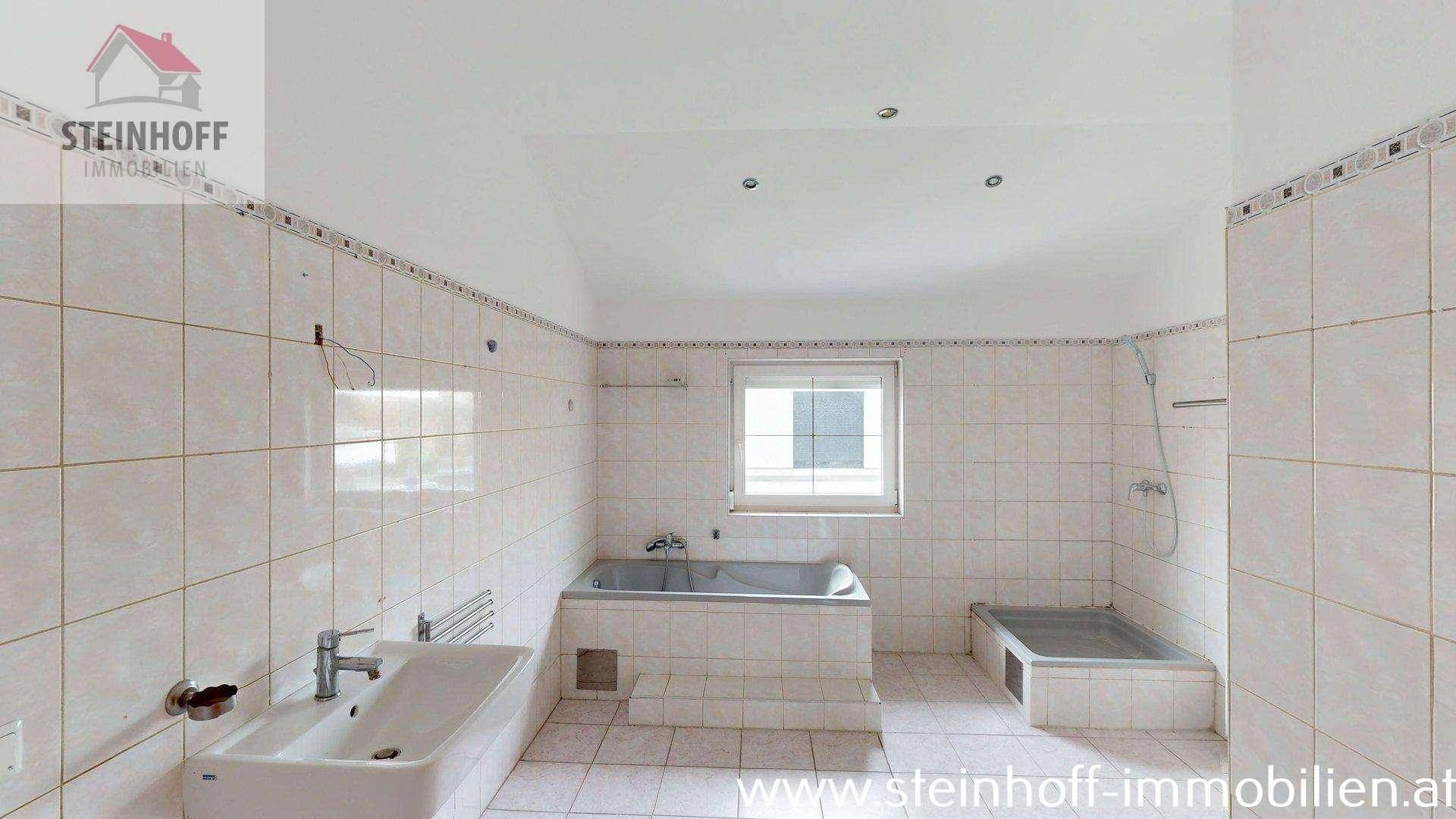 Gefliestes Badezimmer mit Badewanne, Dusche und Fenster, bietet viel Tageslicht.