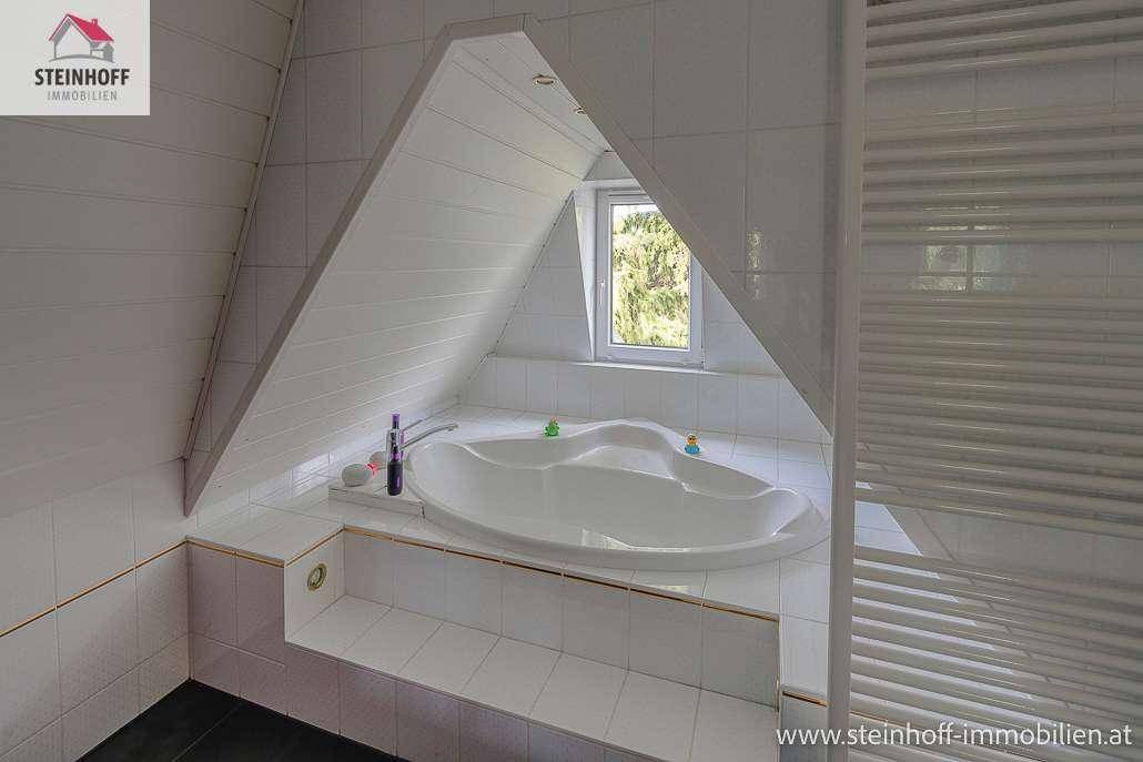 Badezimmer im Dachgeschoss mit großer Eckbadewanne, Dachschräge und Fenster.