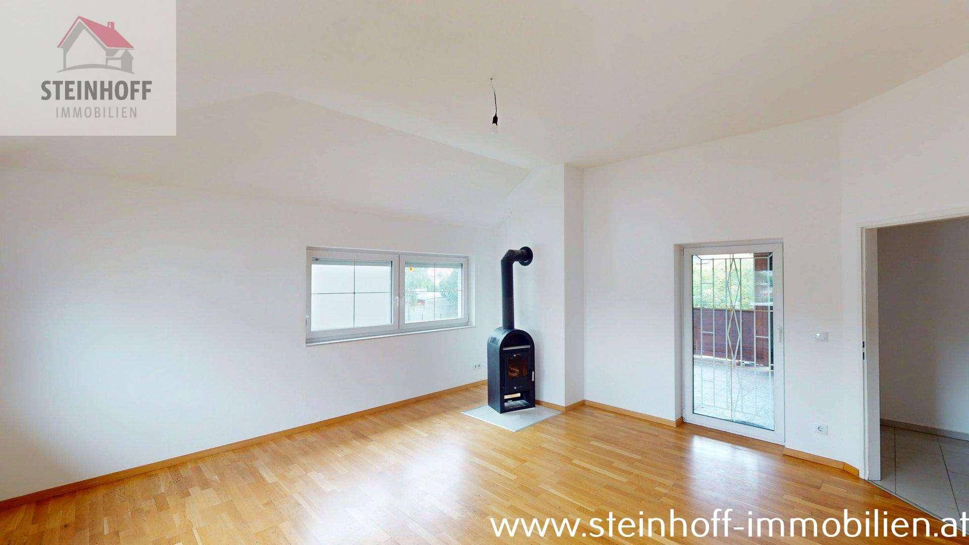 Leeres Wohnzimmer mit Holzboden und Kaminofen, bereit zur individuellen Gestaltung und Nutzung.