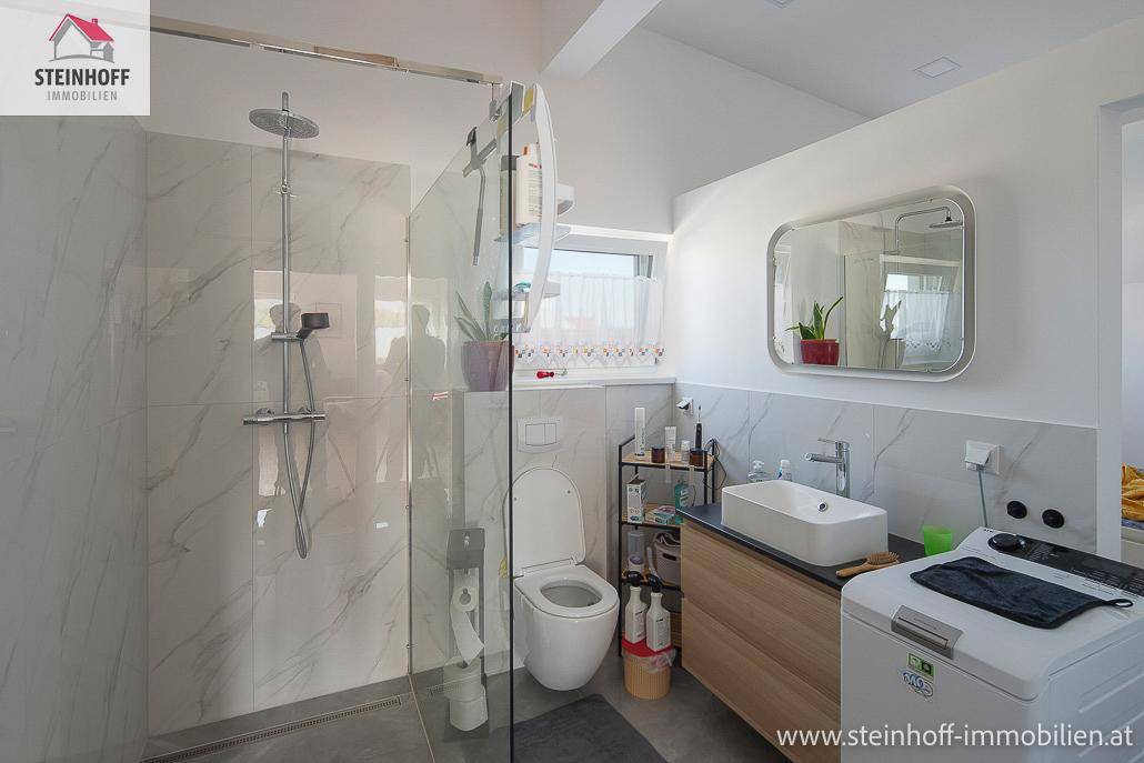 Modernes Badezimmer im Dachgeschoss mit begehbarer Dusche, WC und Waschbecken unter der Dachschräge.