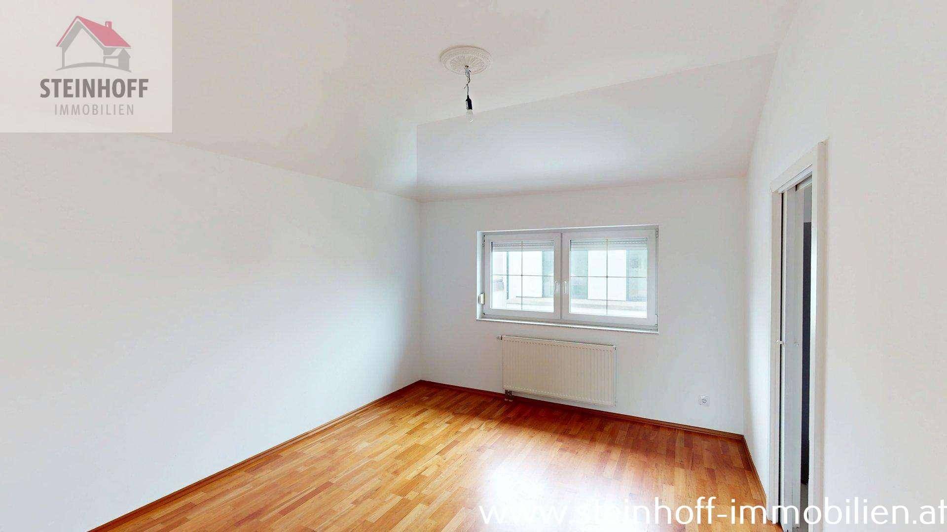 Heller Raum mit Holzboden und Fenster mit Jalousien, vielseitig nutzbar und gepflegt.