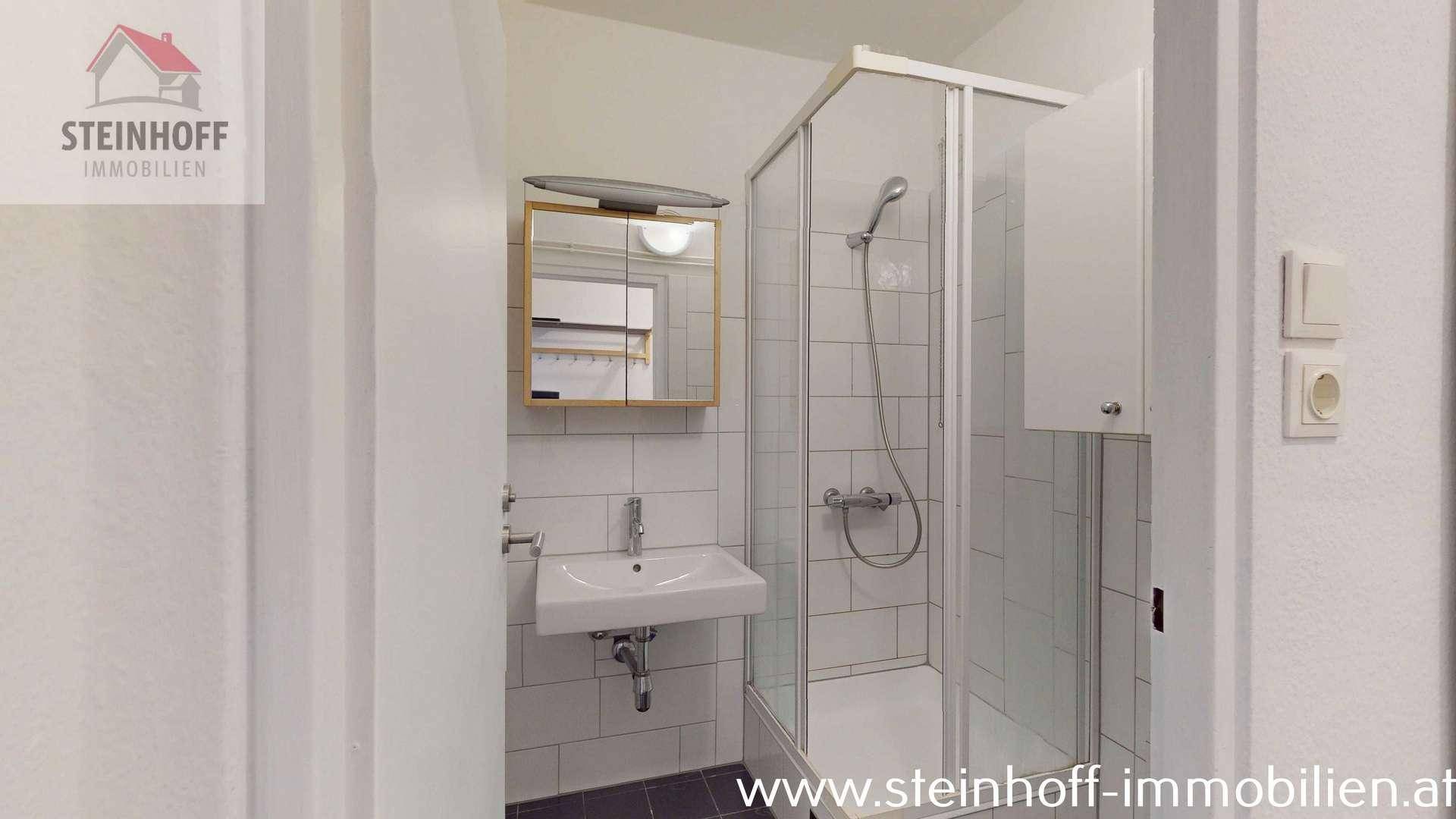 Modernes Badezimmer mit Duschkabine, Waschbecken und Spiegelschrank.