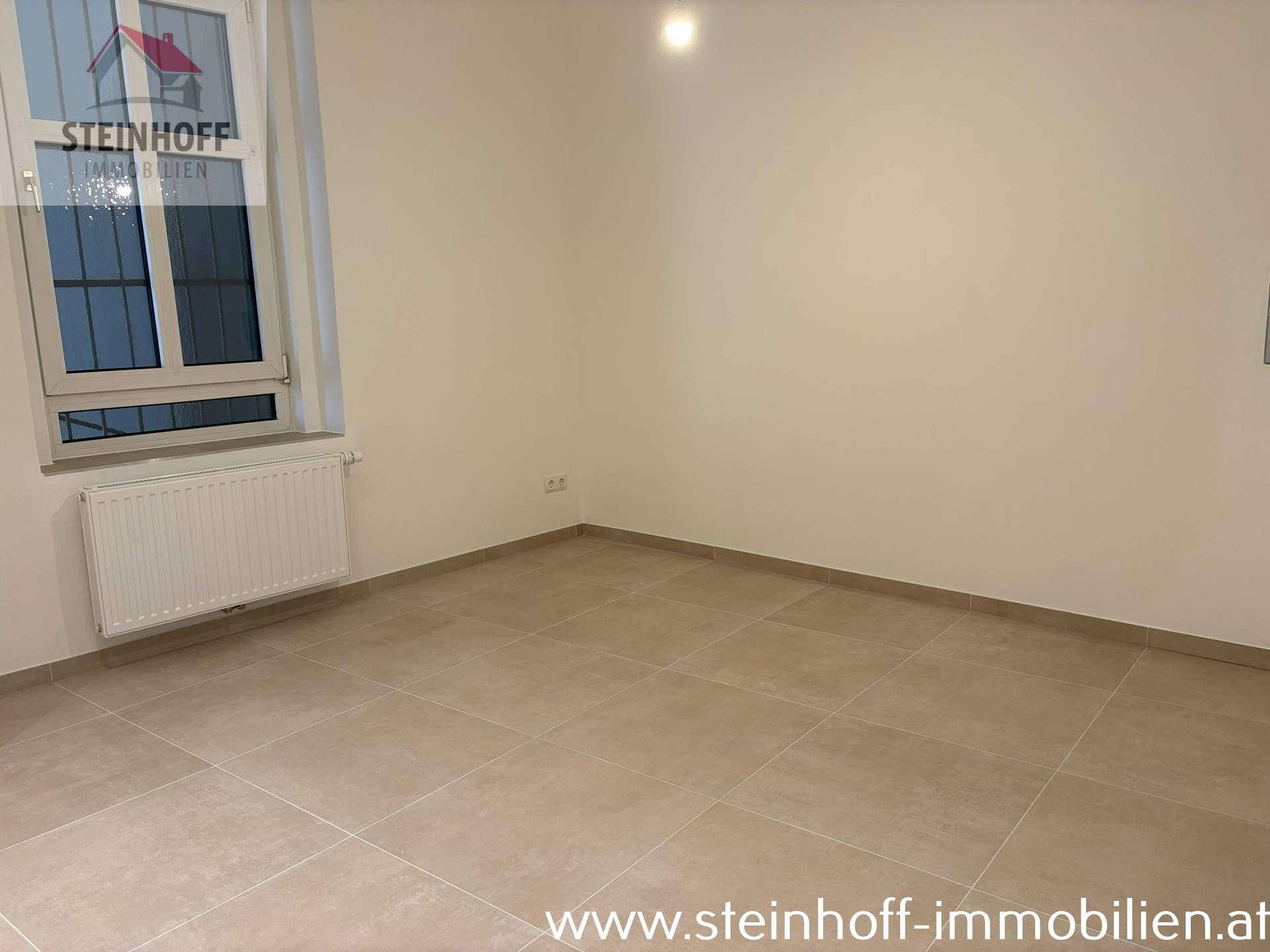 Leeres Zimmer mit hellen Fliesen und einem Fenster, das natürliches Licht in den Raum bringt.