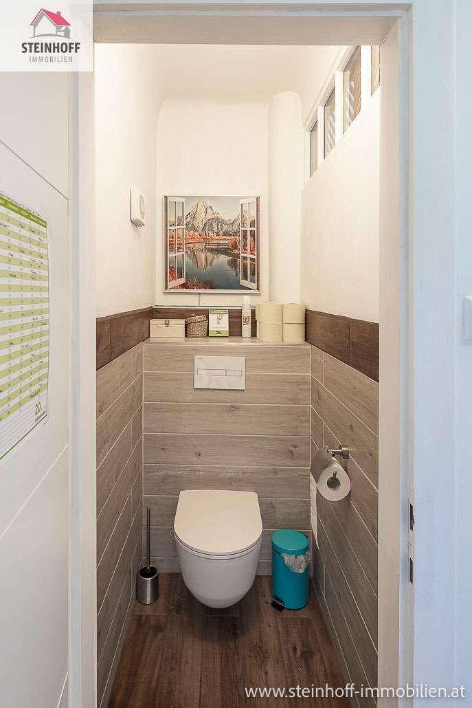 Modern gefliestes Gäste-WC mit wandhängendem WC und Holzoptik-Fliesen.