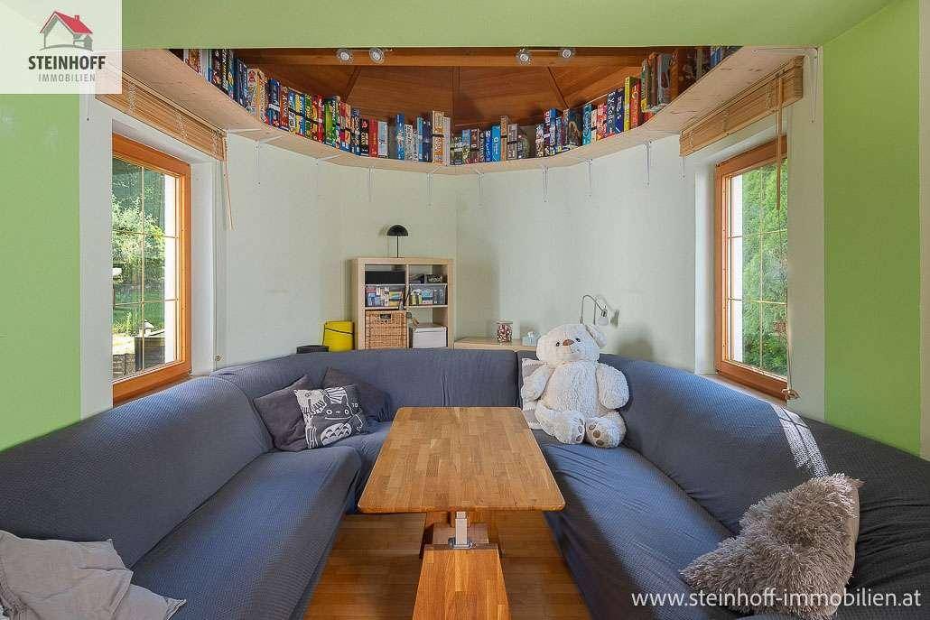 Gemütliche Sitzecke im Wohnzimmer mit integriertem Bücherregal und Blick ins Grüne.
