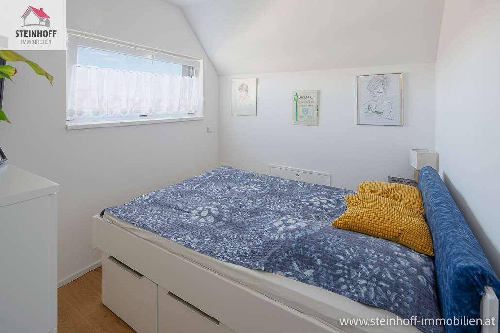 Gemütliches Schlafzimmer im Dachgeschoss mit Bett, Fenster und schräger Decke für eine besondere Atmosphäre.