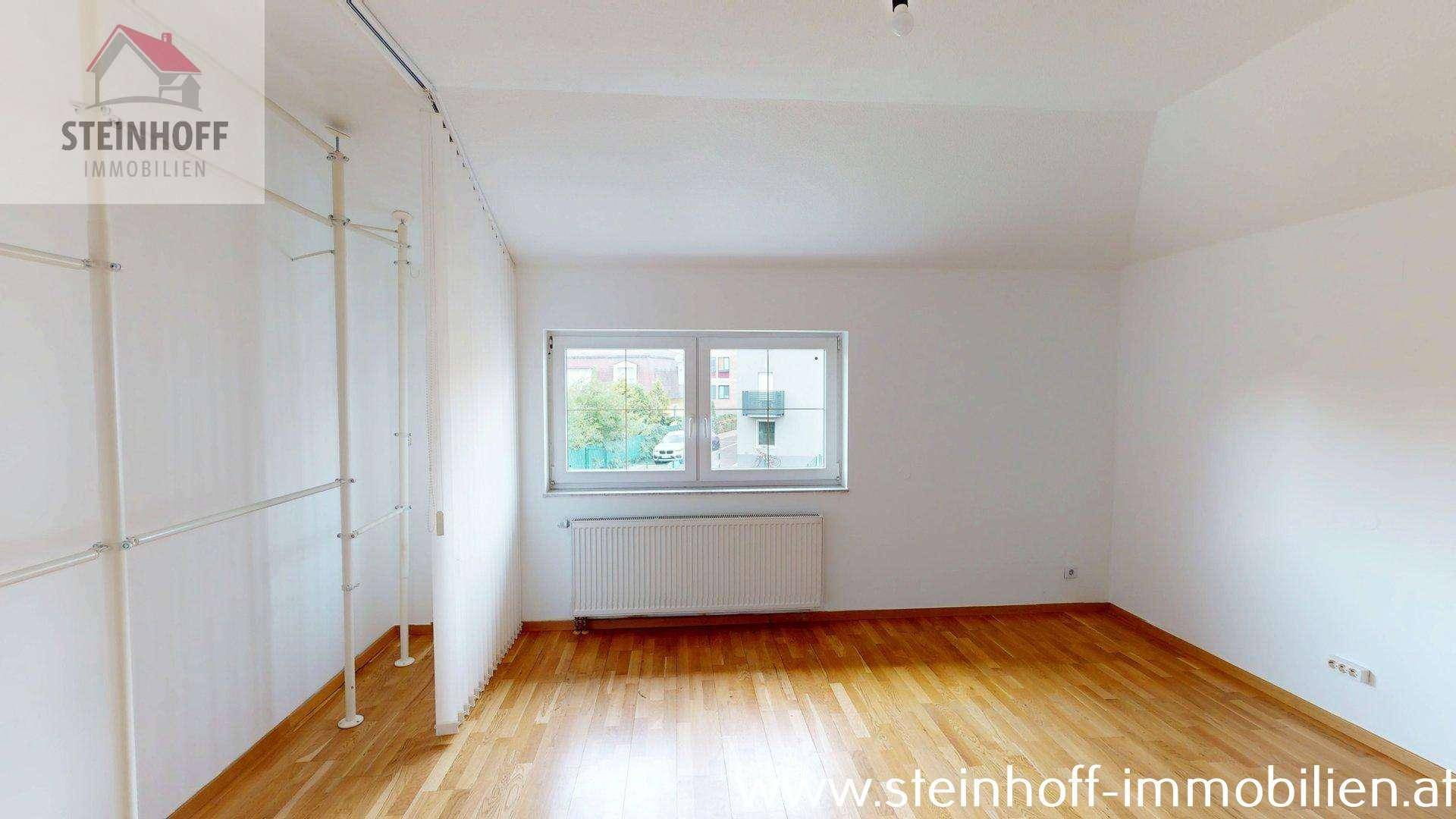 Geräumiges Schlafzimmer mit Holzboden, Fenster und offener Kleideraufbewahrung, hell und funktional.