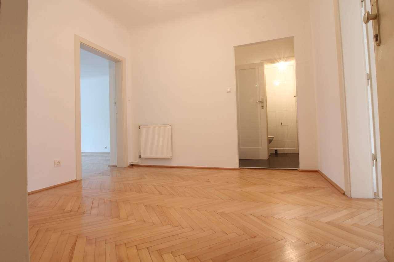 Flur mit Fischgrätparkett und Zugang zu mehreren Zimmern, inklusive Bad oder WC.