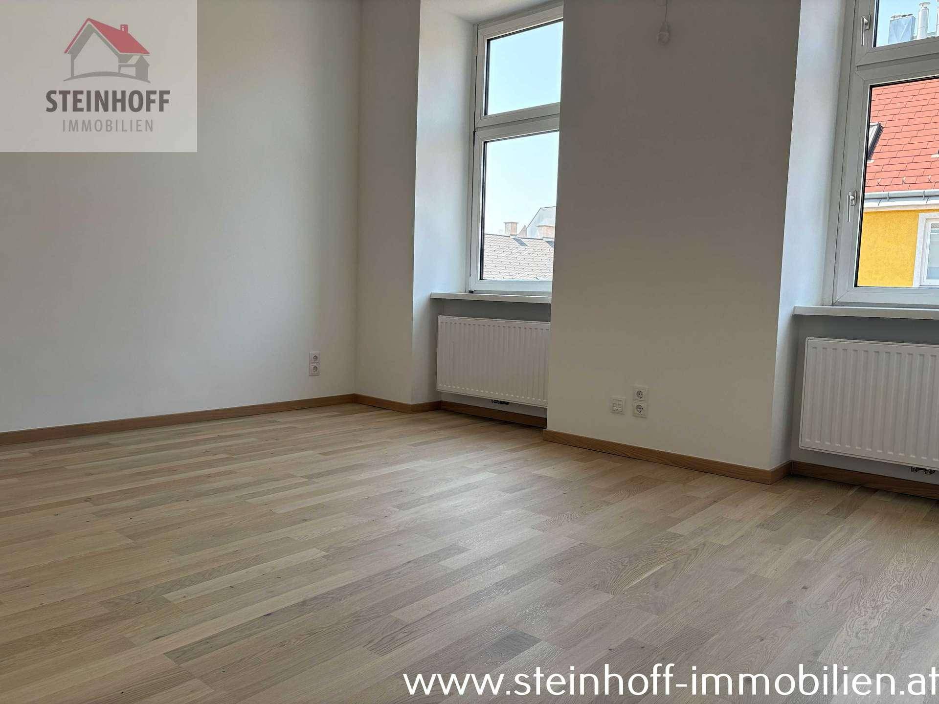 Geräumiges Zimmer mit Parkettboden und zwei Fenstern, die viel Tageslicht hereinlassen.