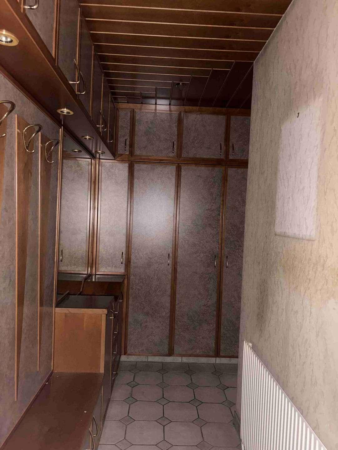 Flur mit Einbauschränken, Holzdecke und gemustertem Fliesenboden, bietet viel Stauraum.