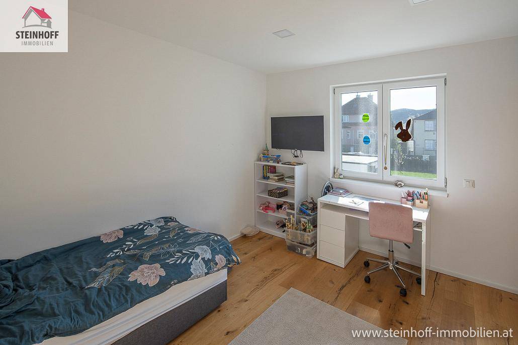Kinderzimmer oder Gästezimmer mit Bett, Schreibtisch und Fenster, hell und funktional eingerichtet.