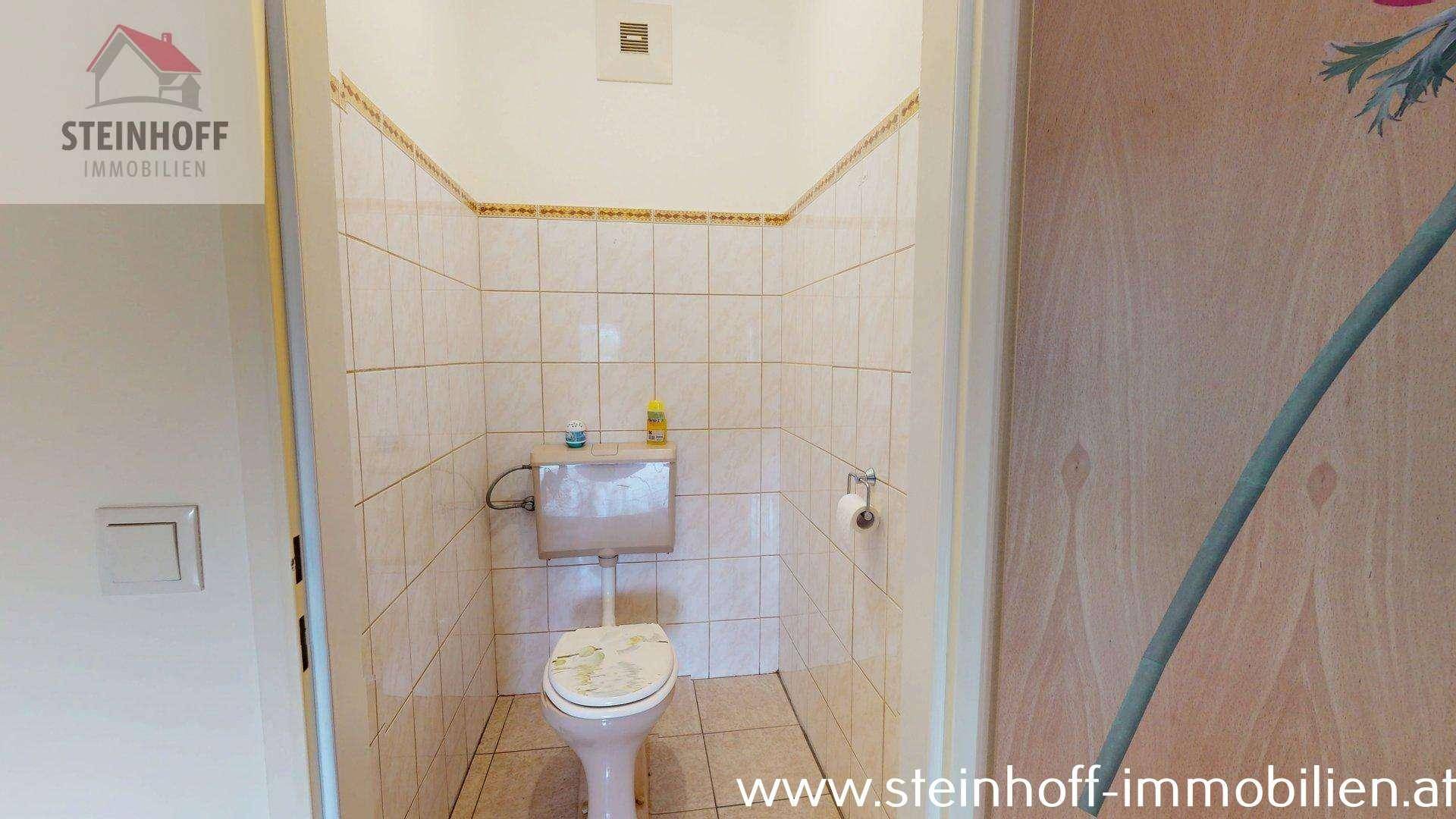 Kleines Gäste-WC mit Fliesen und Toilette, funktional und sauber gehalten.