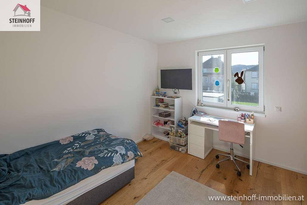 Kinder- oder Gästezimmer mit Einzelbett, Schreibtisch, Regal und Holzboden.