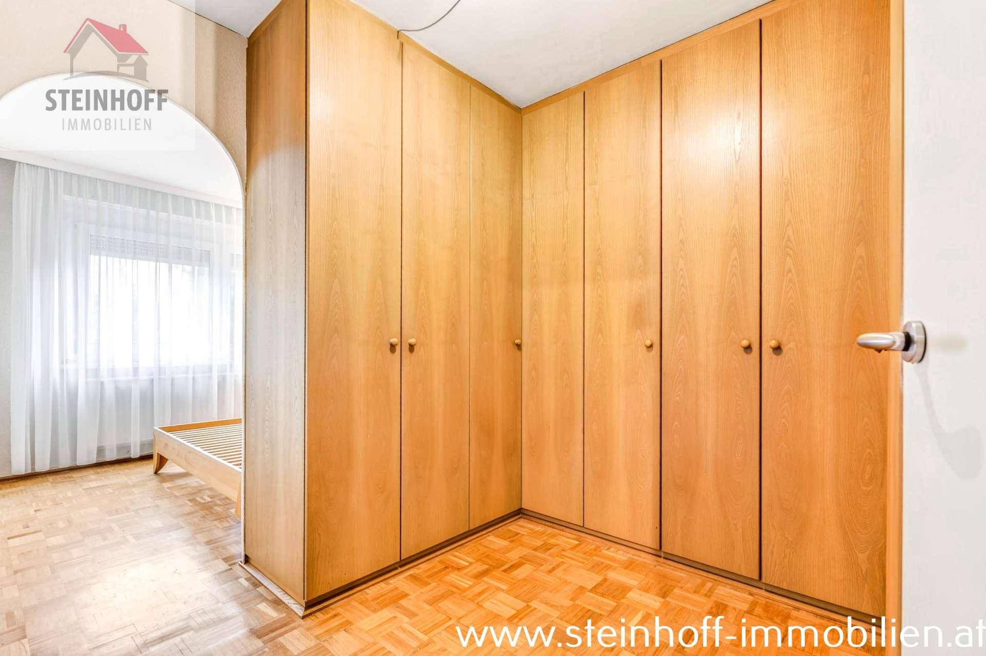 Schlafzimmer mit Holzeinbauschränken und Parkettboden, bietet viel Stauraum und Helligkeit.